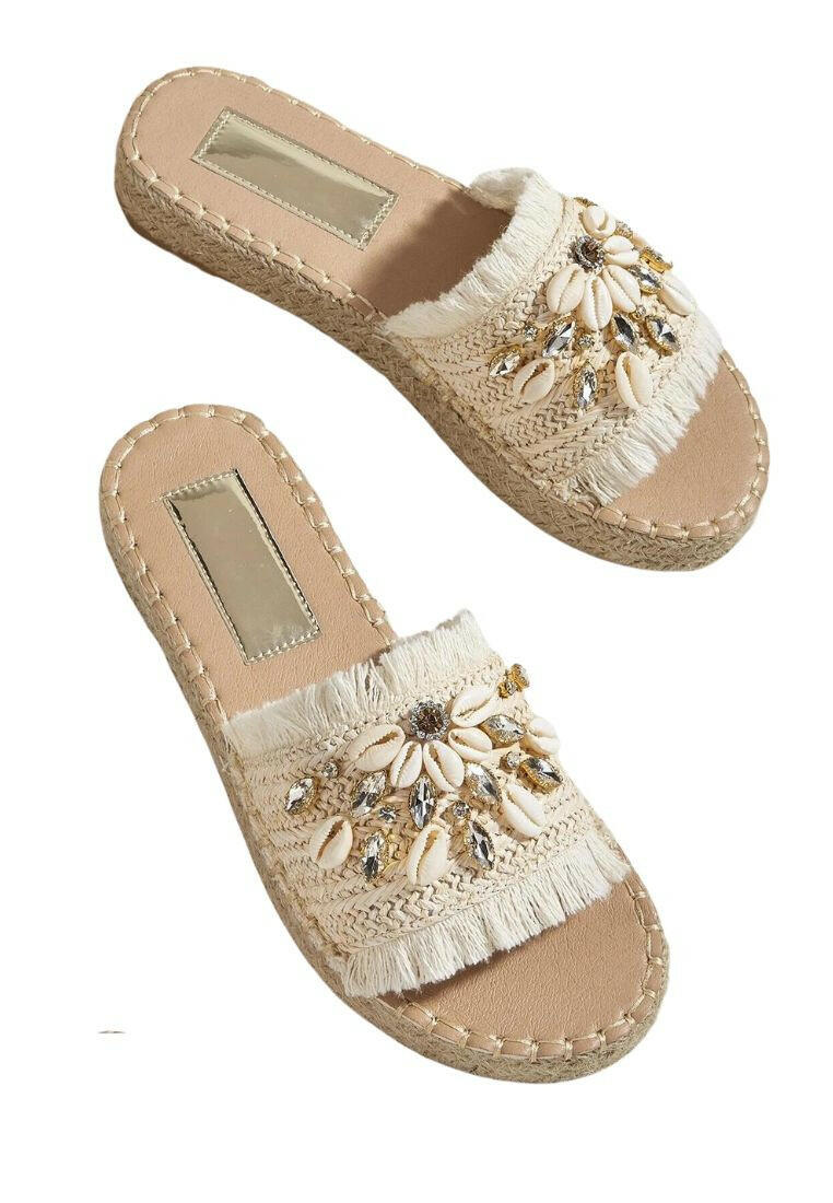 Espadrille sandals adorned with rhinestones and shell decorations. The rhinestones and shells add a touch of elegance and beachy charm to these stylish sandals. Perfect for adding a hint of sparkle and a coastal vibe to your summer outfits.