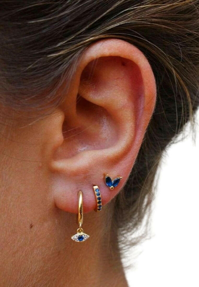 A set of three fashionable silver earrings featuring cubic zirconia and eye decorations. The earrings showcase a combination of sparkling cubic zirconia stones and intricate eye motifs. The silver setting adds a touch of elegance, while the unique design brings a mix of glamour and symbolism to these versatile accessories.