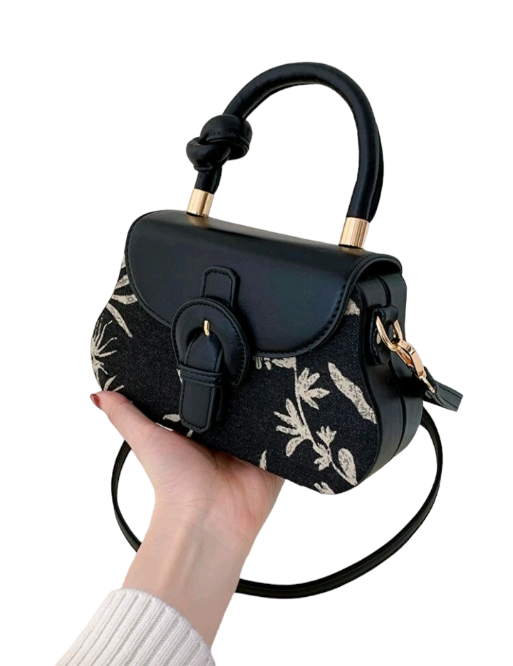 An image of a flap square bag adorned with a plant pattern and decorative buckle. This stylish handbag features an elegant plant-themed design and a unique buckle ornament, adding a touch of nature-inspired charm to your accessory collection.
