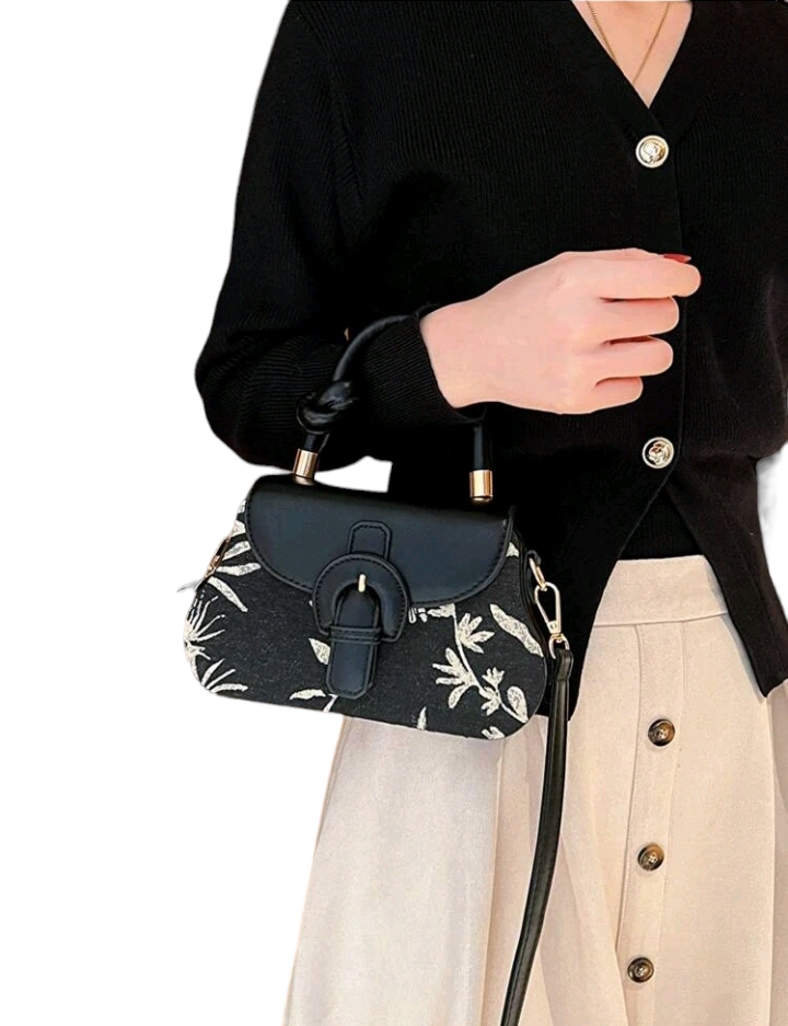 An image of a flap square bag adorned with a plant pattern and decorative buckle. This stylish handbag features an elegant plant-themed design and a unique buckle ornament, adding a touch of nature-inspired charm to your accessory collection.