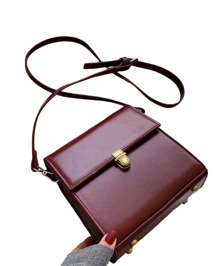 A burgundy mini push-button flap square bag. This compact bag has a square shape and a deep burgundy color. It features a push-button flap closure and is designed as a fashionable accessory for carrying small items or essentials.