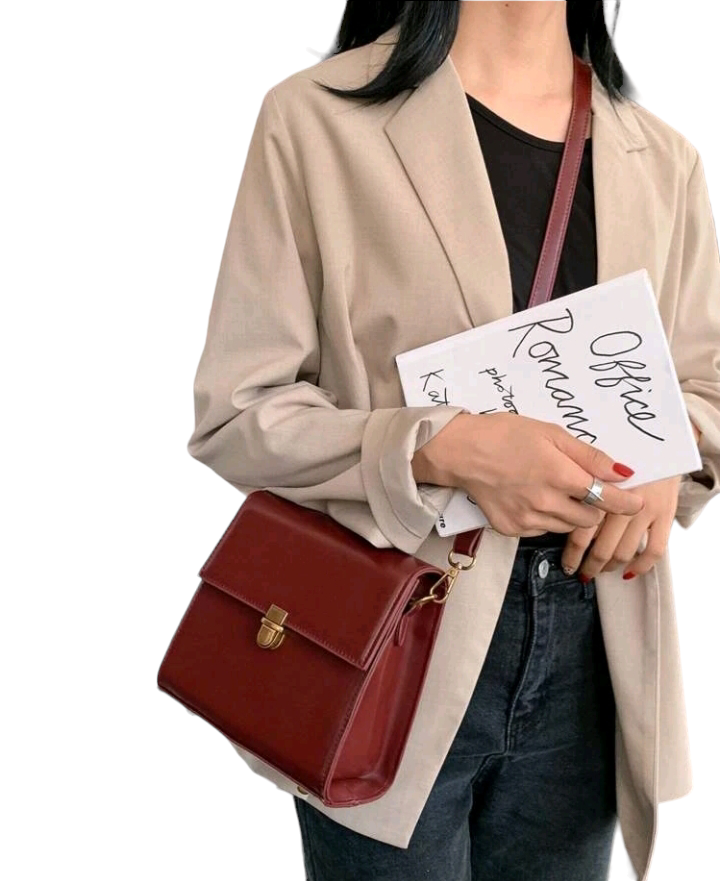 A burgundy mini push-button flap square bag. This compact bag has a square shape and a deep burgundy color. It features a push-button flap closure and is designed as a fashionable accessory for carrying small items or essentials.