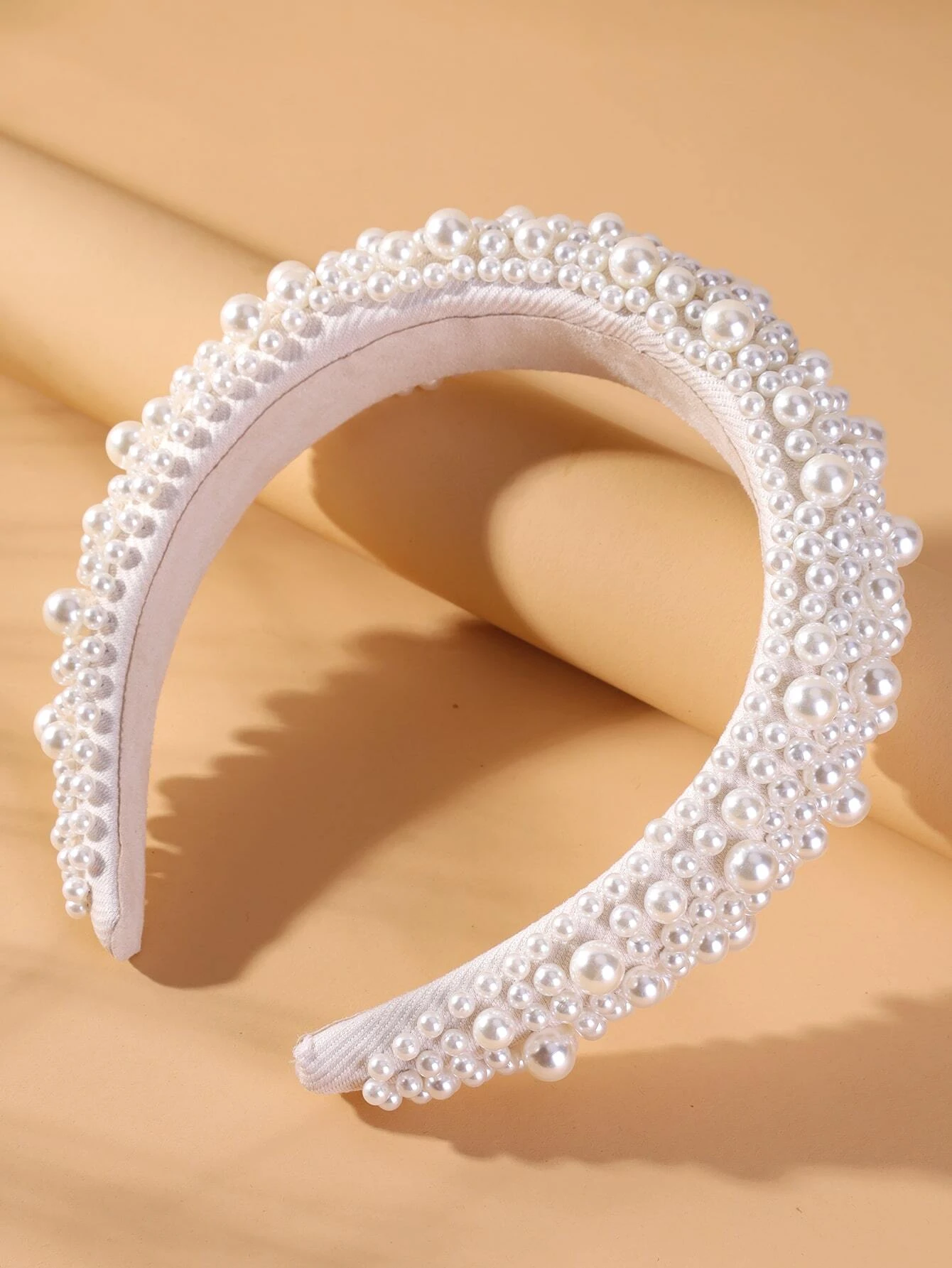 Wide headband adorned with white faux pearls, offering a chic and stylish accessory to elevate your hair look.