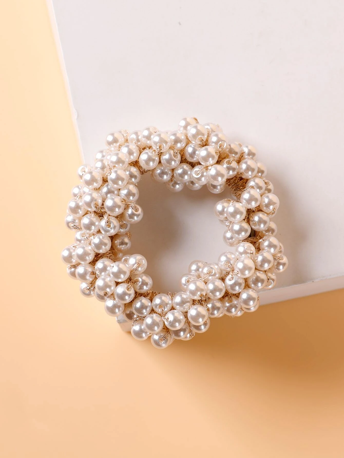 A single hair tie adorned with faux pearls, offering a stylish and elegant way to accessorize and enhance your hairstyle.