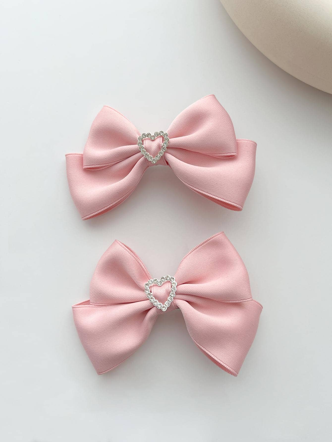 Two alligator hair clips featuring rhinestone heart and bow decorations, combining charm and sparkle for a delightful addition to your hairstyle.
