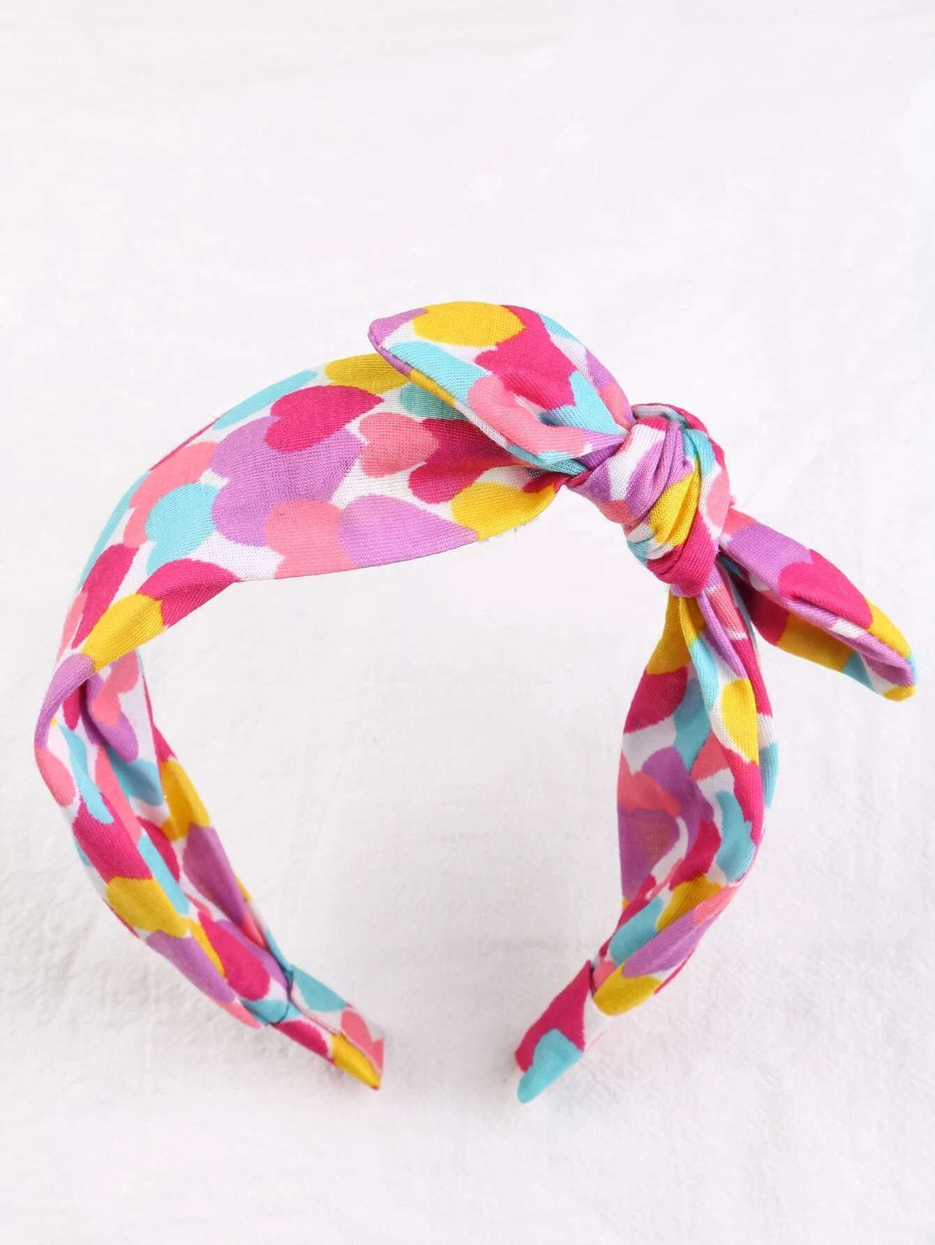 Headband adorned with a heart print bow decoration, designed for toddler girls to add a cute and stylish accessory to their hair look.