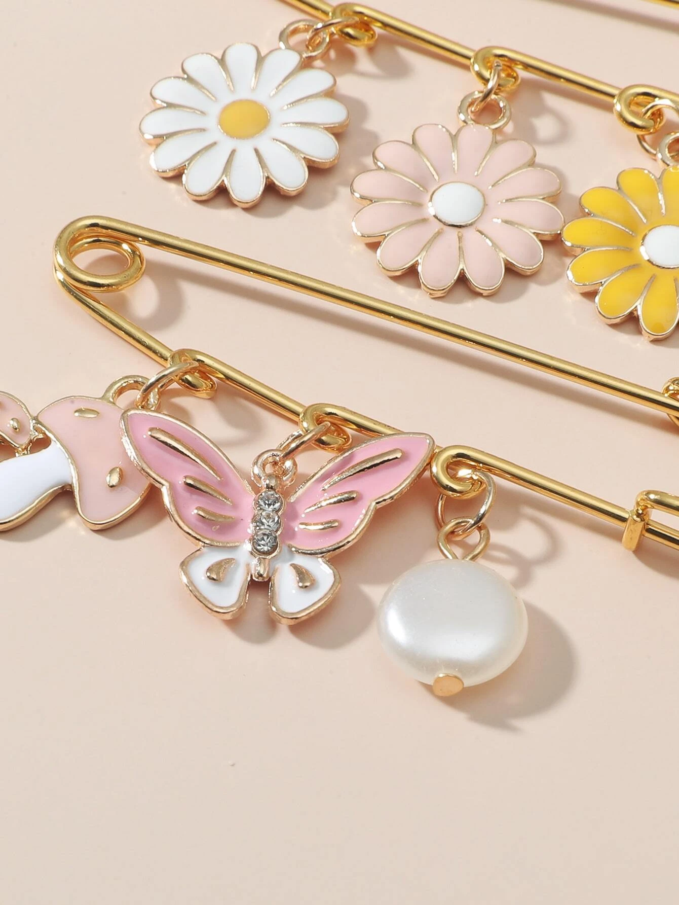 Set of two safety pin brooches adorned with flower charms, combining functionality and style to accessorize your clothing or accessories with a touch of floral elegance.