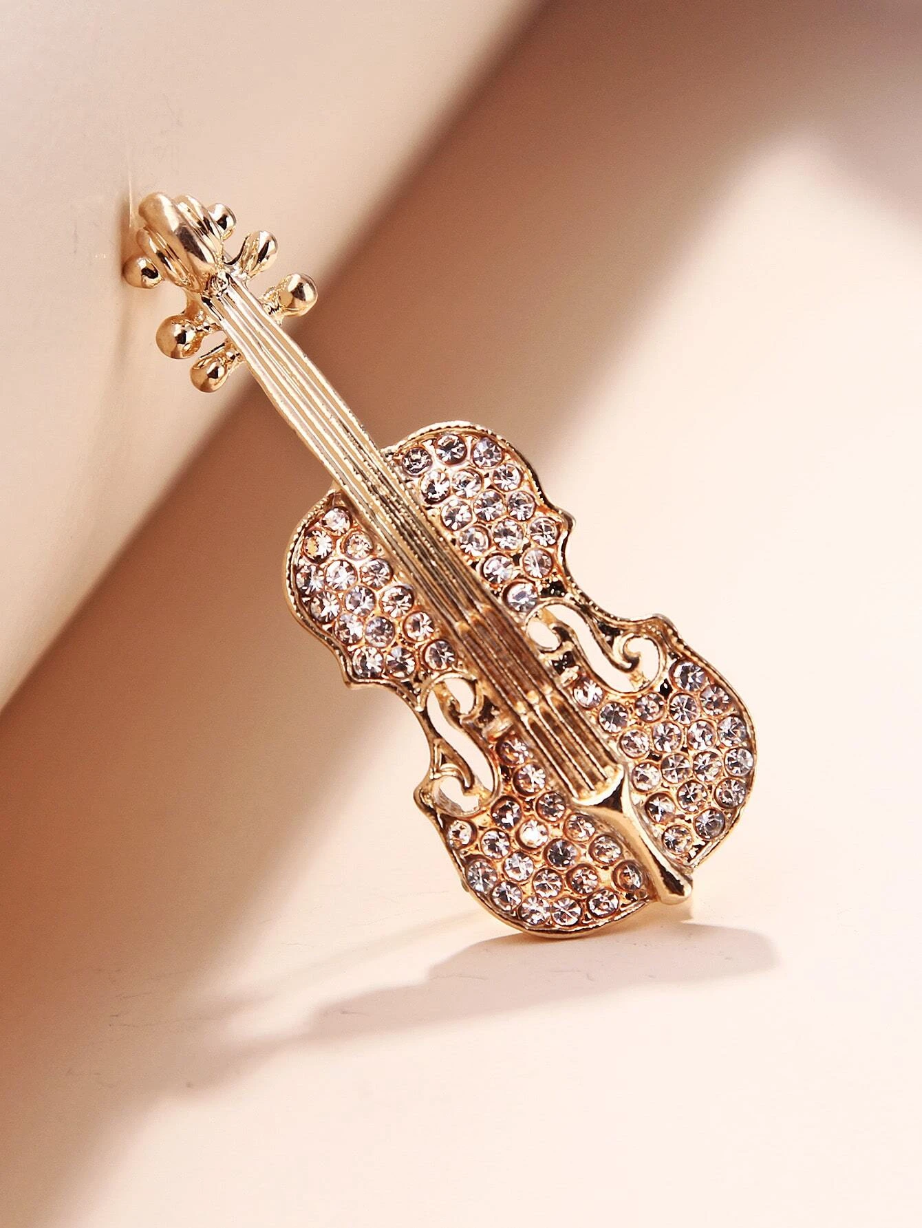 Brooch featuring a violin design, adorned with shimmering rhinestones, capturing the elegance and beauty of music in a glamorous and artistic accessory.