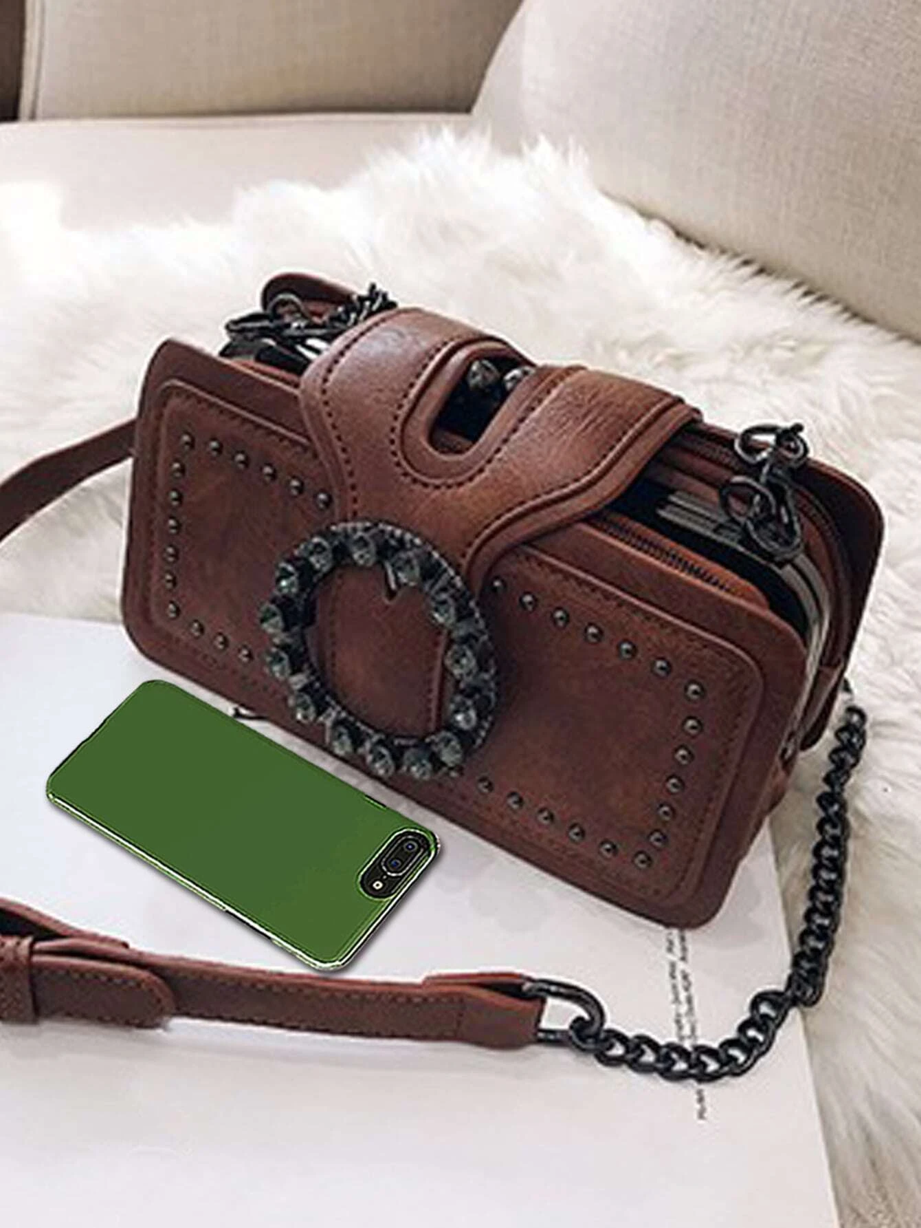 Square bag adorned with studded and buckle decorations. This accessory adds a touch of edgy style to your ensemble, featuring a combination of studs and buckles that enhance its visual appeal.