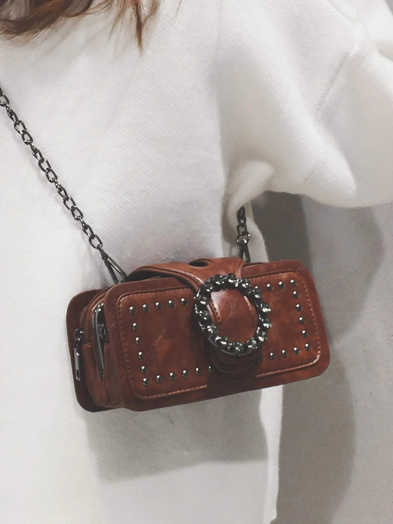 Square bag adorned with studded and buckle decorations. This accessory adds a touch of edgy style to your ensemble, featuring a combination of studs and buckles that enhance its visual appeal.