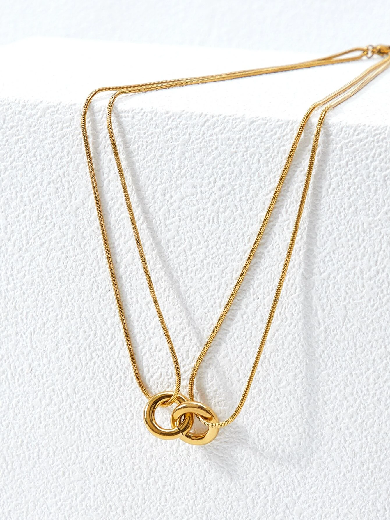 Layered necklace with round decorative elements. The necklace features multiple tiers of circular pendants in various sizes and textures, creating a visually dynamic and stylish piece. The interplay of metallic finishes and patterns adds depth to the design, making it a versatile and trendy accessory to elevate any outfit.