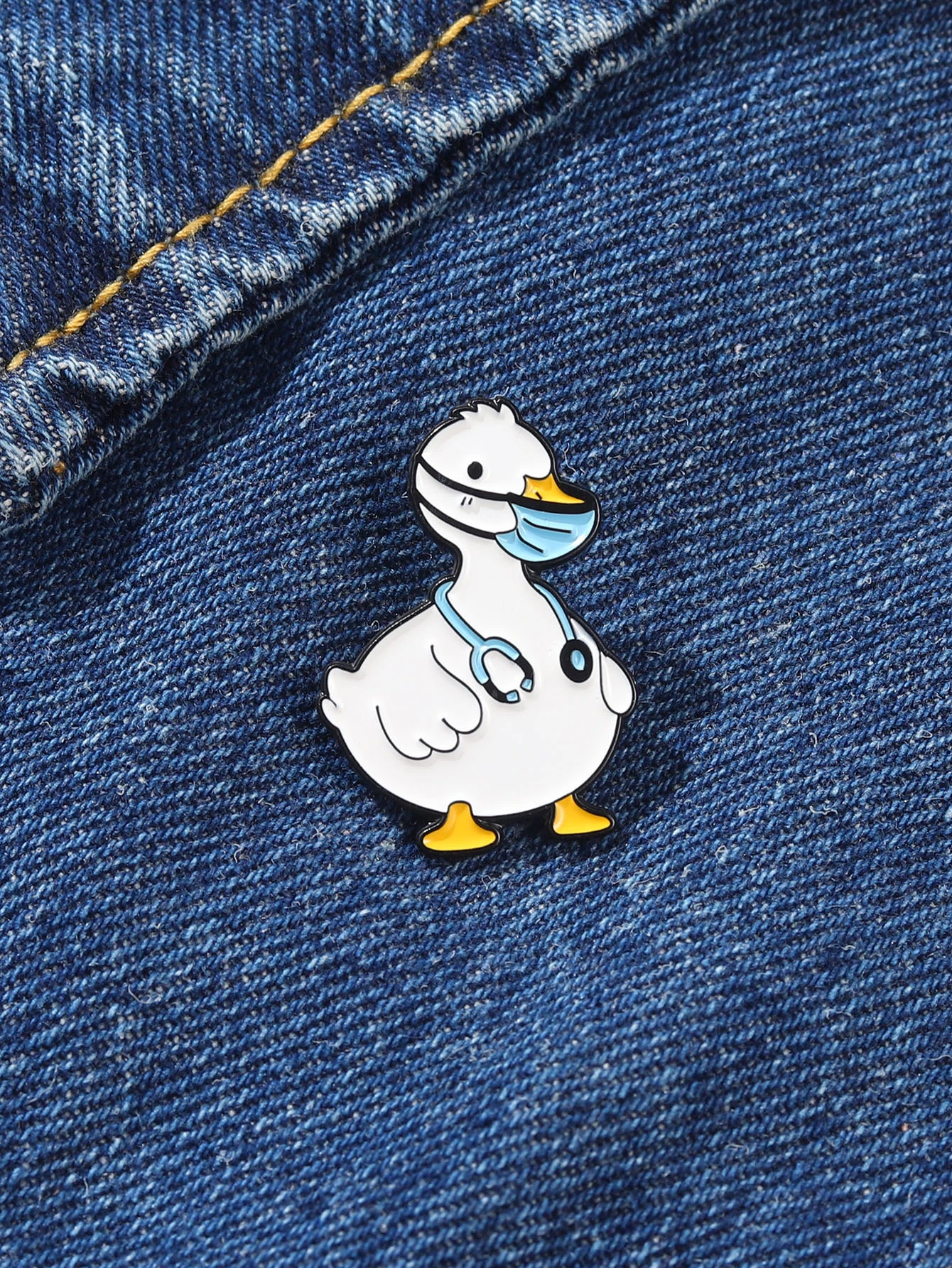 Colorful cartoon duck brooch with a cheerful expression, vibrant yellow feathers, an orange beak, and large, expressive eyes. The brooch is intricately designed, capturing the playful nature of a duck in a whimsical and artistic style.