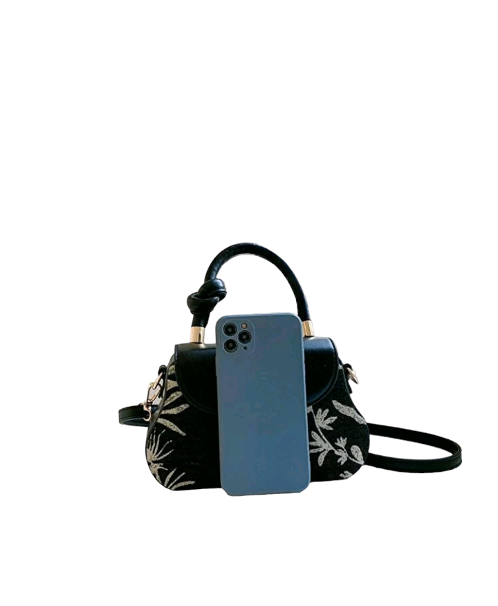 An image of a flap square bag adorned with a plant pattern and decorative buckle. This stylish handbag features an elegant plant-themed design and a unique buckle ornament, adding a touch of nature-inspired charm to your accessory collection.