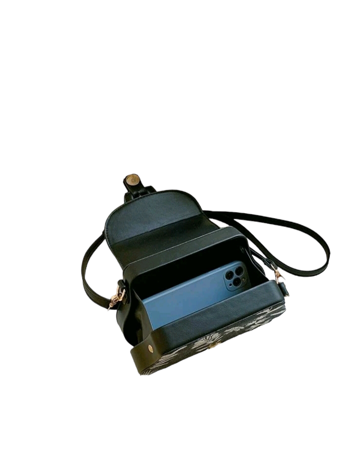 An image of a flap square bag adorned with a plant pattern and decorative buckle. This stylish handbag features an elegant plant-themed design and a unique buckle ornament, adding a touch of nature-inspired charm to your accessory collection.