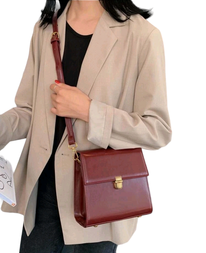 A burgundy mini push-button flap square bag. This compact bag has a square shape and a deep burgundy color. It features a push-button flap closure and is designed as a fashionable accessory for carrying small items or essentials.