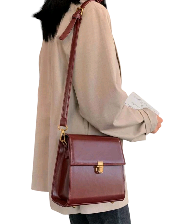A burgundy mini push-button flap square bag. This compact bag has a square shape and a deep burgundy color. It features a push-button flap closure and is designed as a fashionable accessory for carrying small items or essentials.