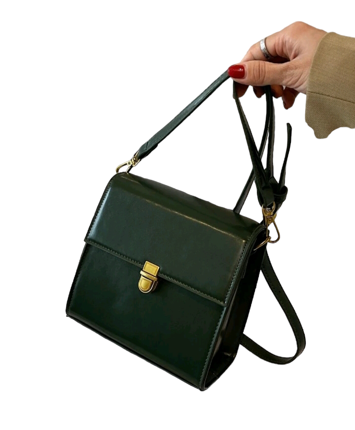 A dark green mini flap square bag with intricate stitch detailing. This compact bag has a square shape with a rich dark green hue. It showcases meticulous stitching on its surface and is designed as a stylish accessory for carrying small items or essentials with flair.