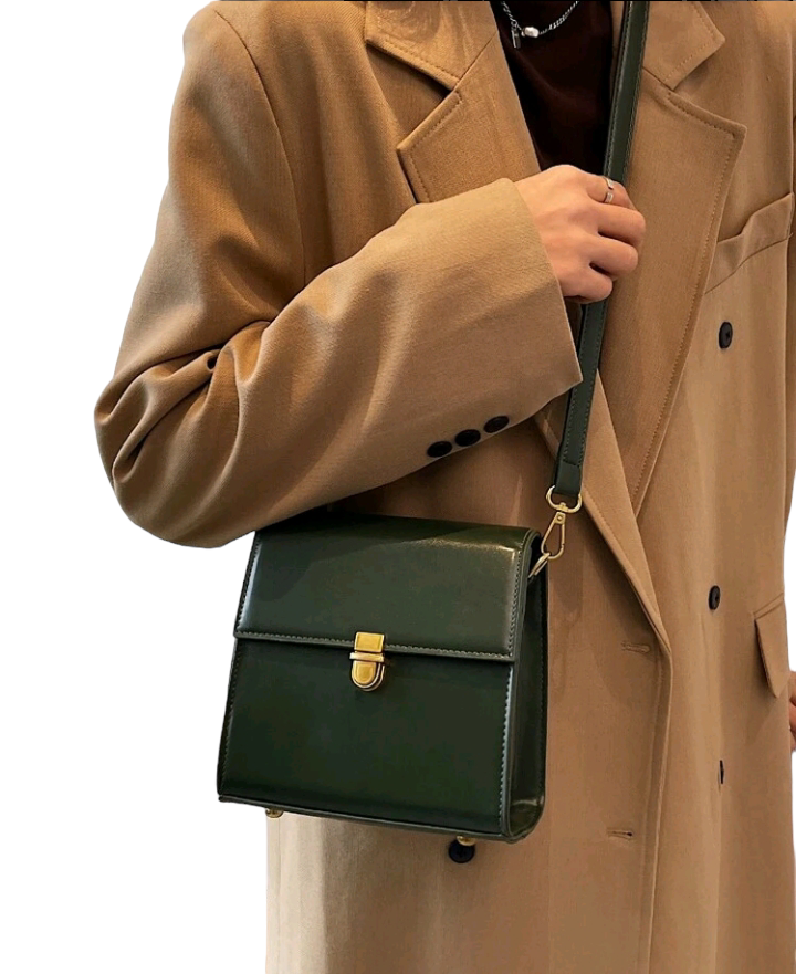 A dark green mini flap square bag with intricate stitch detailing. This compact bag has a square shape with a rich dark green hue. It showcases meticulous stitching on its surface and is designed as a stylish accessory for carrying small items or essentials with flair.