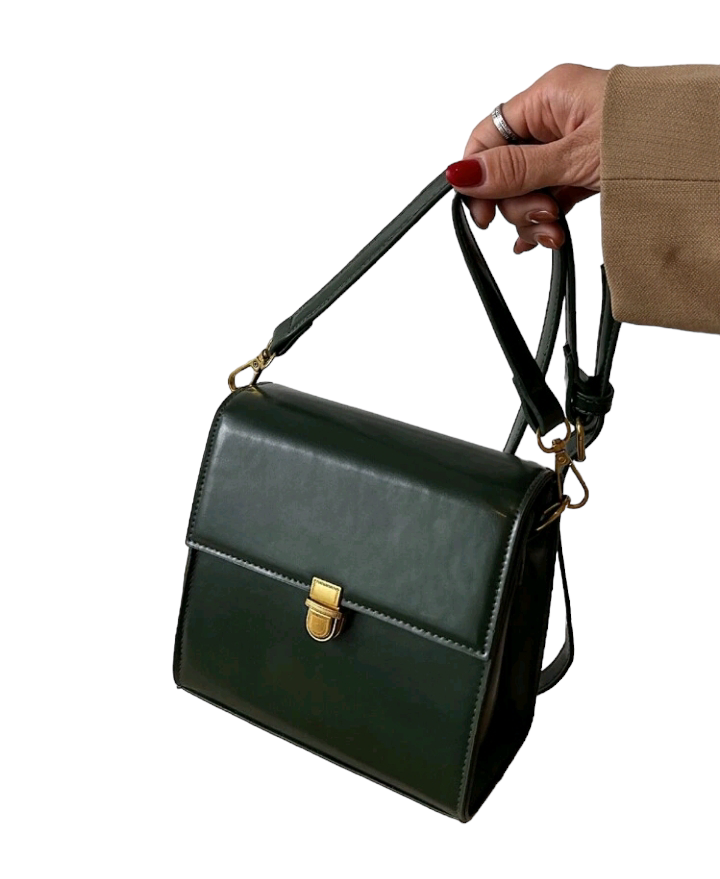 A dark green mini flap square bag with intricate stitch detailing. This compact bag has a square shape with a rich dark green hue. It showcases meticulous stitching on its surface and is designed as a stylish accessory for carrying small items or essentials with flair.