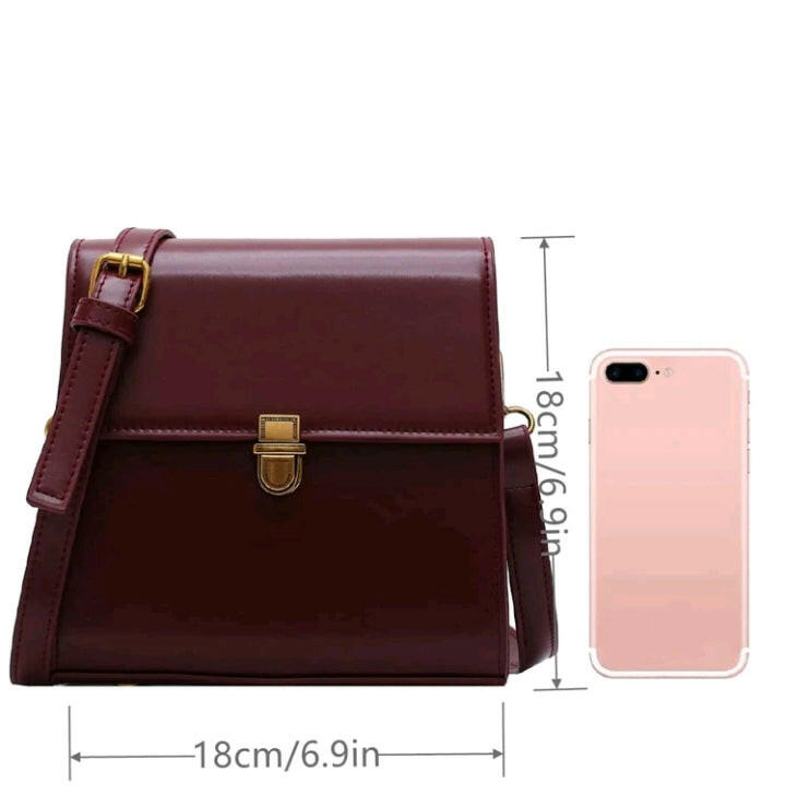 A burgundy mini push-button flap square bag. This compact bag has a square shape and a deep burgundy color. It features a push-button flap closure and is designed as a fashionable accessory for carrying small items or essentials.