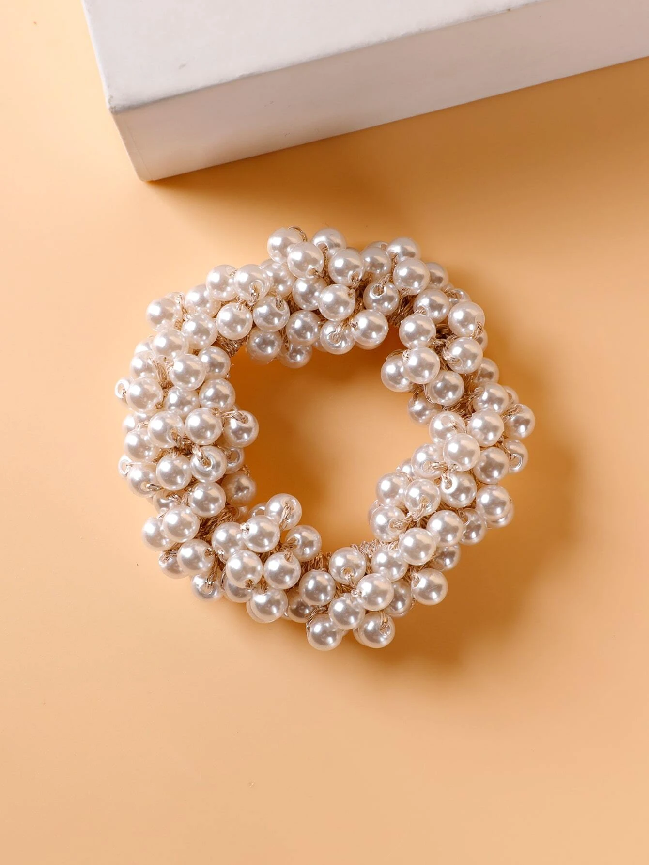 A single hair tie adorned with faux pearls, offering a stylish and elegant way to accessorize and enhance your hairstyle.