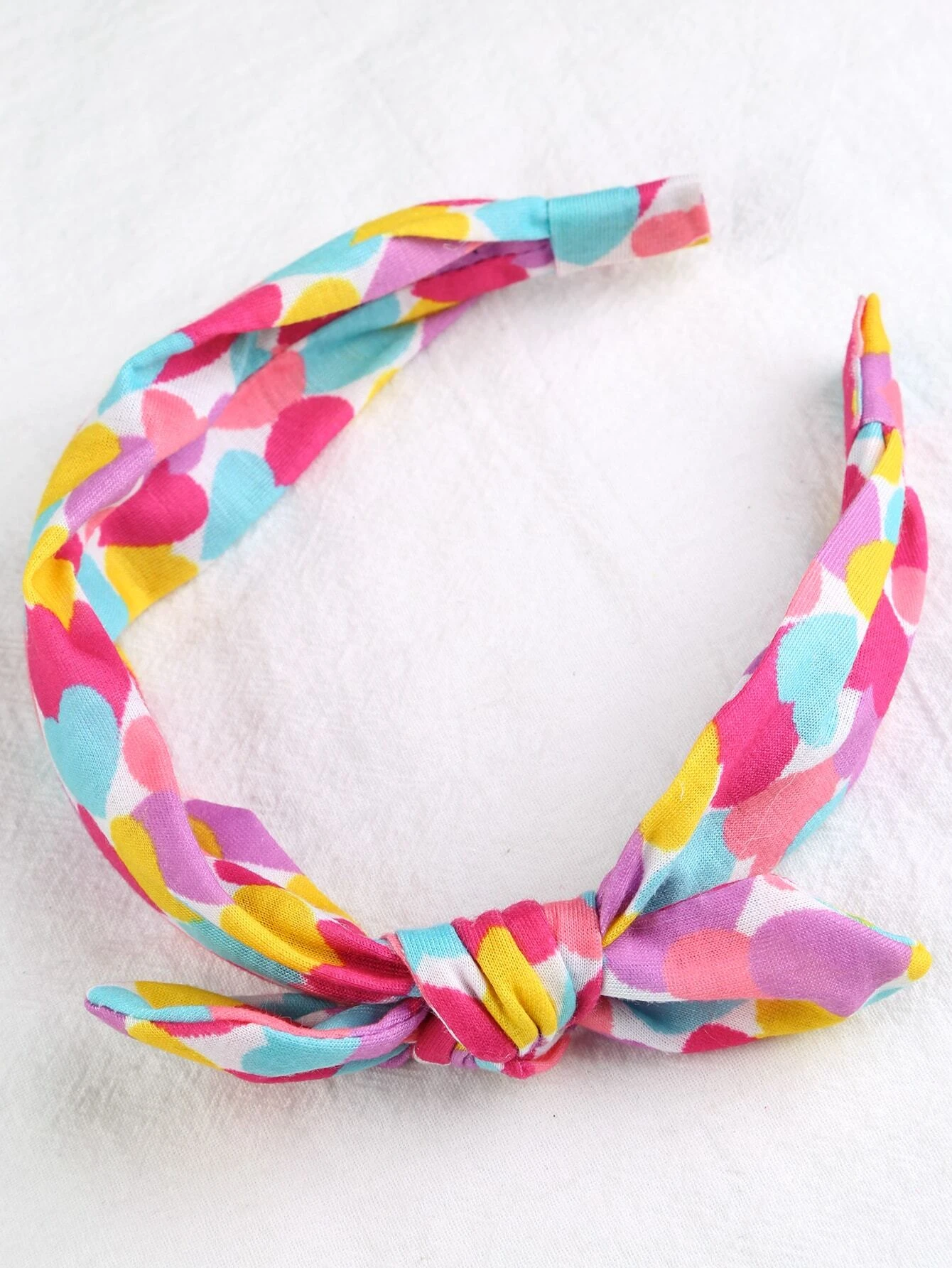 Headband adorned with a heart print bow decoration, designed for toddler girls to add a cute and stylish accessory to their hair look.