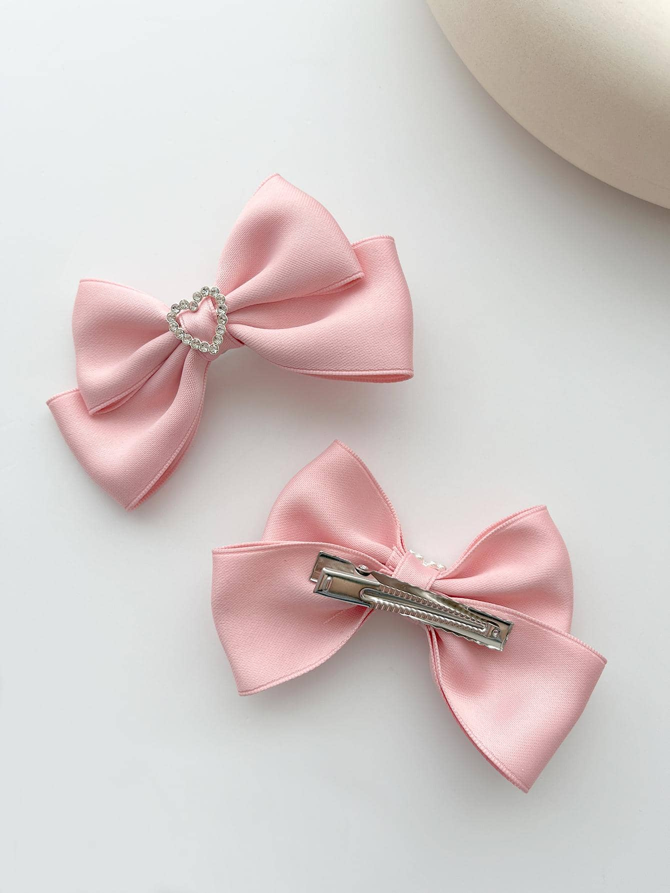 Two alligator hair clips featuring rhinestone heart and bow decorations, combining charm and sparkle for a delightful addition to your hairstyle.