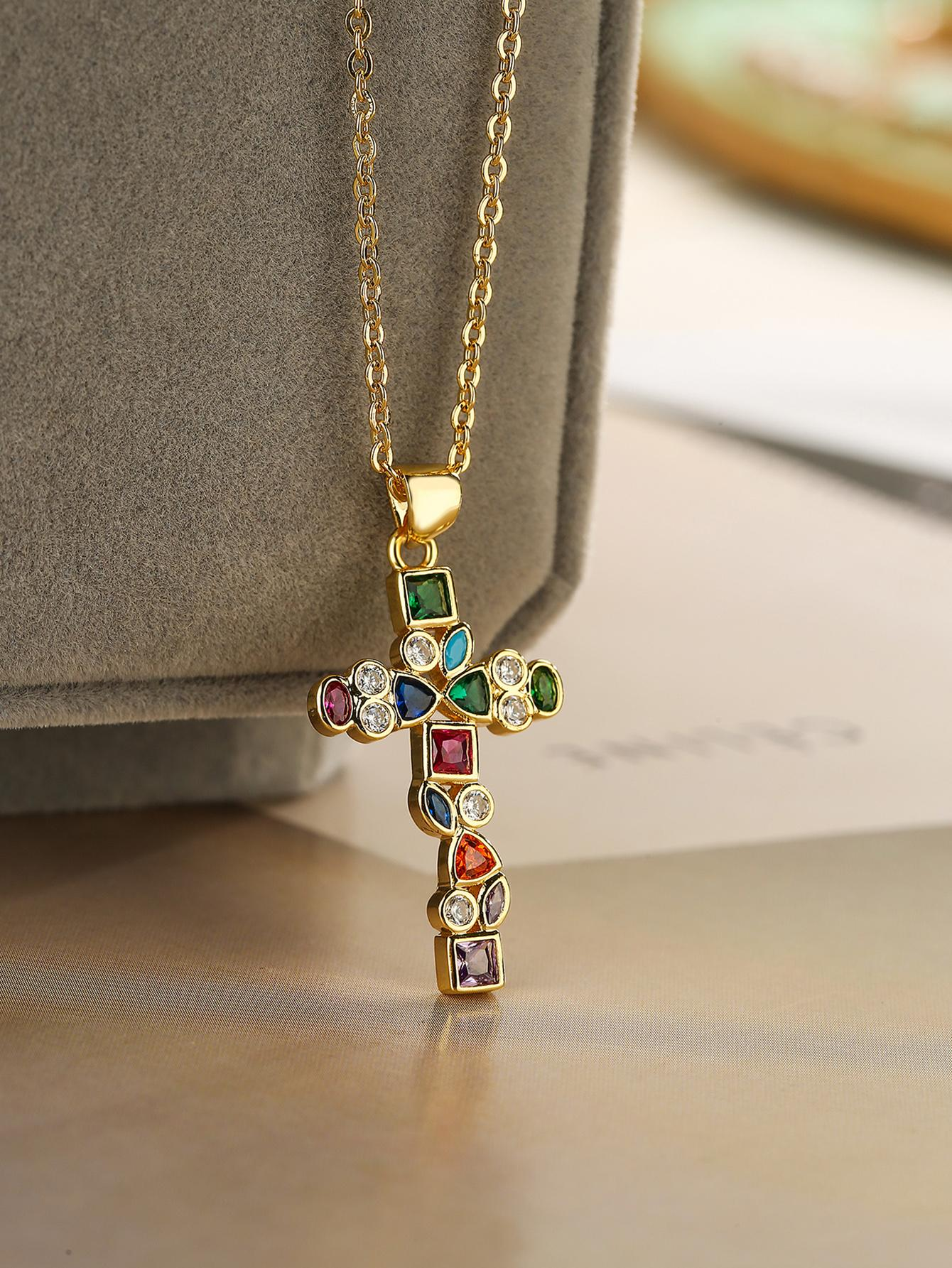 A necklace featuring a colorful cubic zirconia cross charm pendant. The pendant showcases a cross design adorned with vibrant cubic zirconia gemstones in various colors, suspended from a delicate chain. This necklace is both eye-catching and symbolic, adding a touch of elegance and spiritual significance to different outfits.