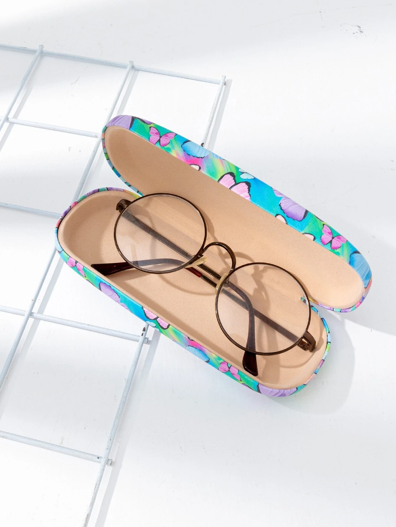  A glasses case featuring a butterfly print design. The case is designed to store and protect eyeglasses, sunglasses, or other optical frames. The butterfly print adds a touch of whimsy and style to the case. This accessory is both functional and fashionable, providing a secure and stylish storage solution for eyewear.