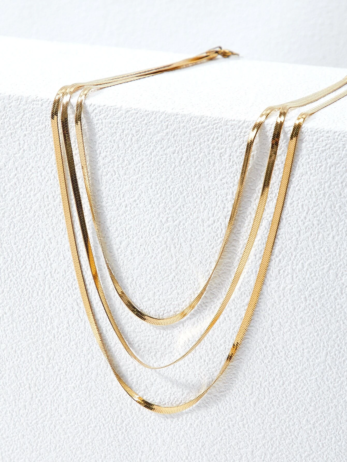 A layered necklace with a minimalist design. The necklace features delicate chains arranged in layers, creating a simple and elegant look. This accessory is modern and versatile, adding a touch of understated sophistication to various outfits