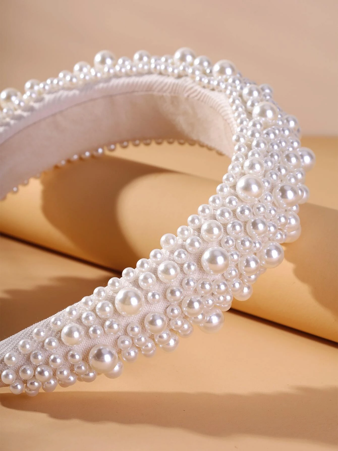 Wide headband adorned with white faux pearls, offering a chic and stylish accessory to elevate your hair look.