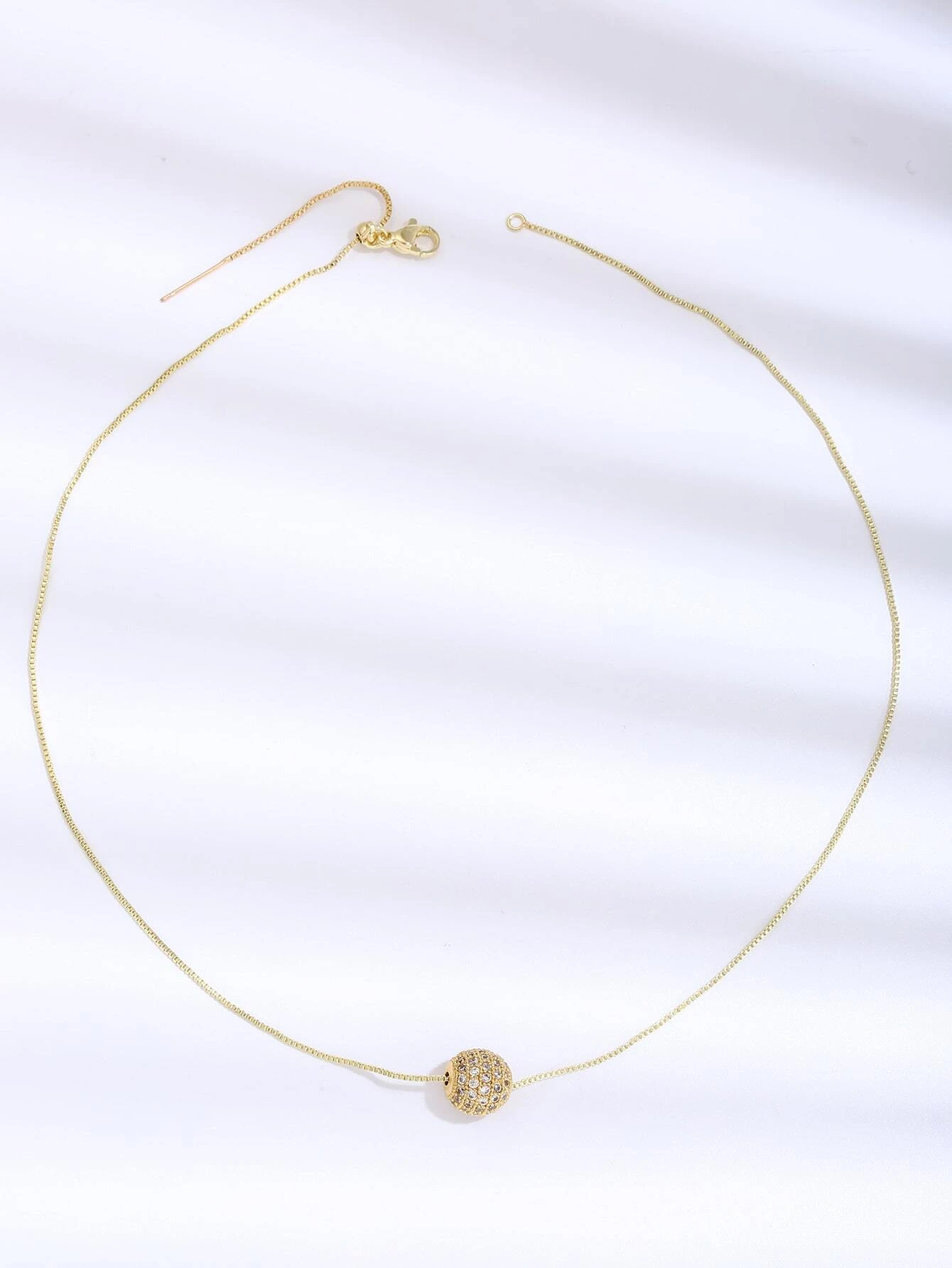 A necklace featuring a cubic zirconia ball charm pendant. The pendant showcases a round charm adorned with cubic zirconia gemstones, suspended from a delicate chain. This necklace is both elegant and versatile, adding a touch of glamour and sparkle to different outfits.