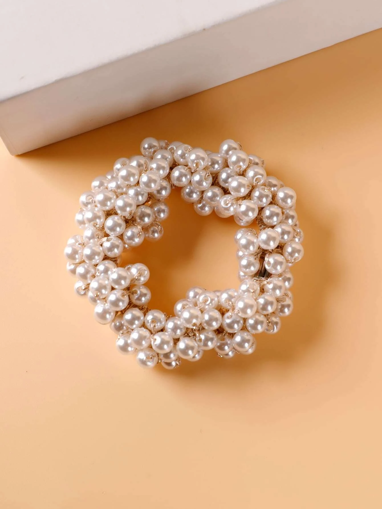 A single hair tie adorned with faux pearls, offering a stylish and elegant way to accessorize and enhance your hairstyle.