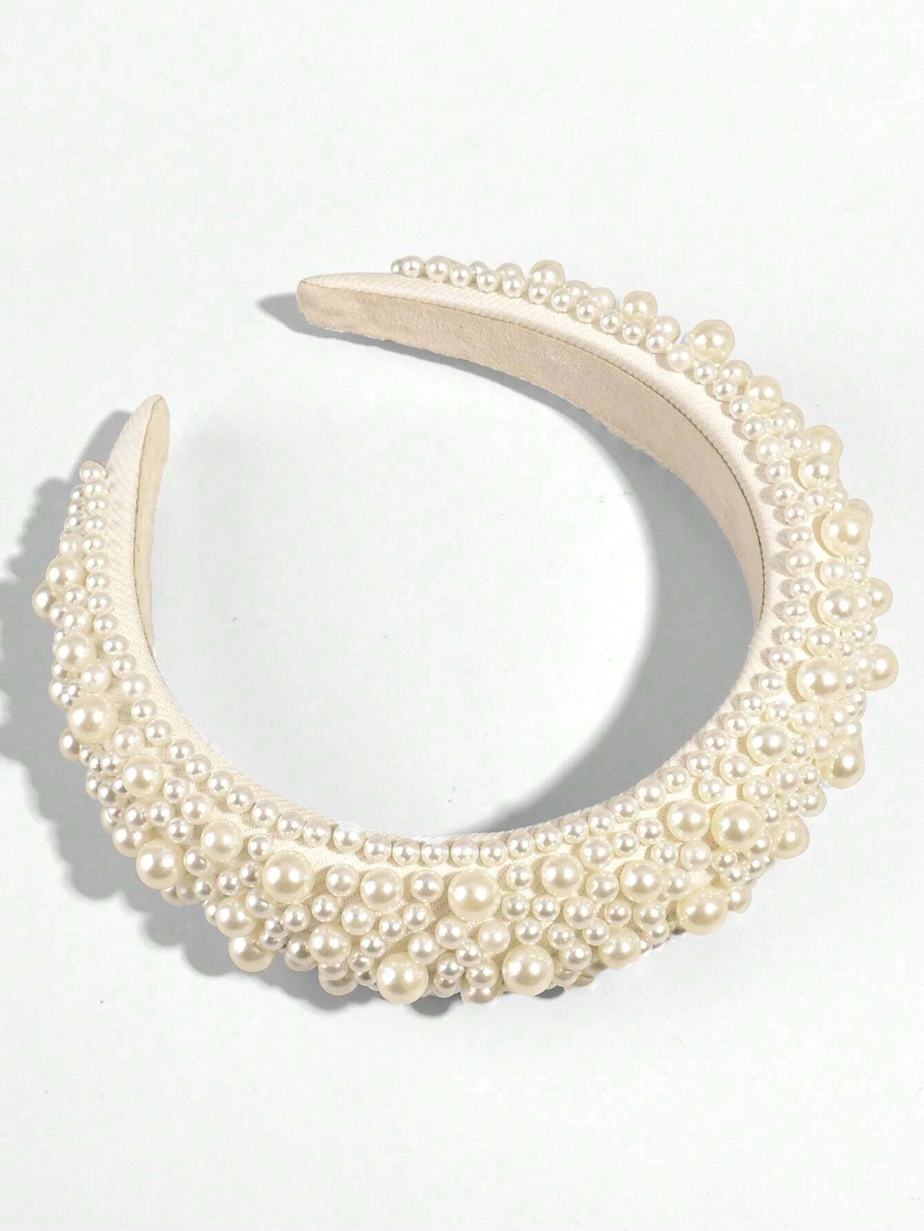 Wide headband adorned with white faux pearls, offering a chic and stylish accessory to elevate your hair look.
