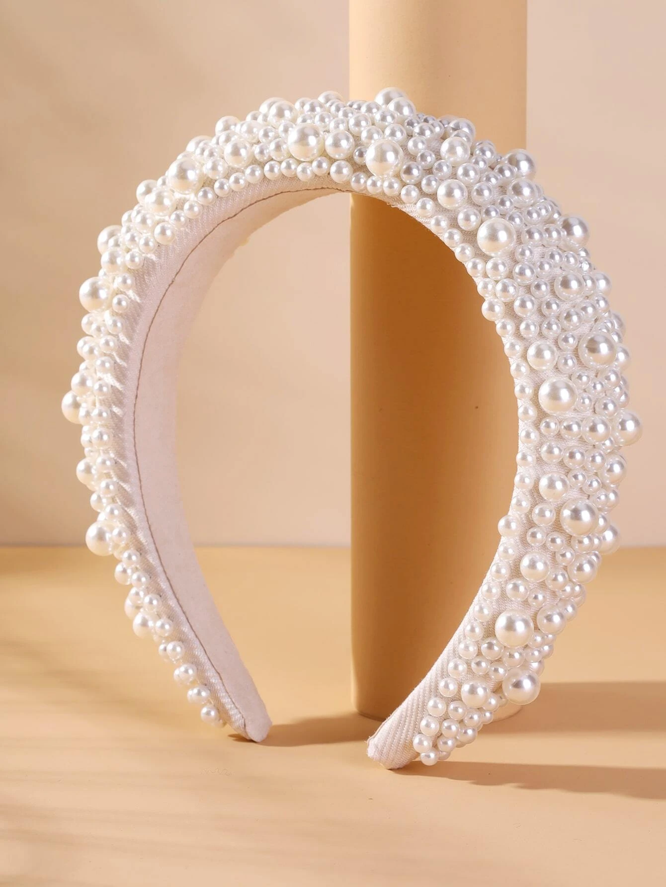 Wide headband adorned with white faux pearls, offering a chic and stylish accessory to elevate your hair look.