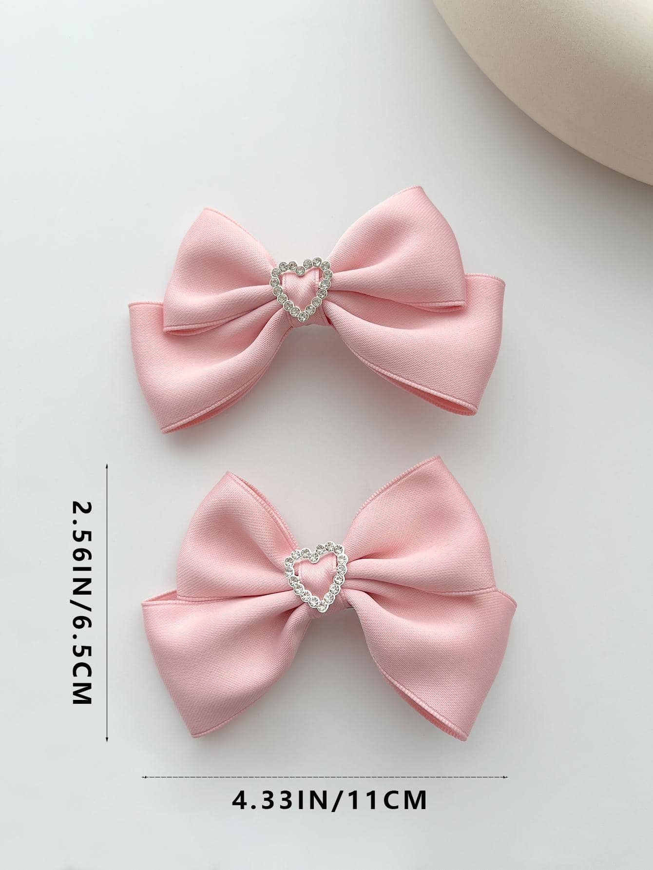 Two alligator hair clips featuring rhinestone heart and bow decorations, combining charm and sparkle for a delightful addition to your hairstyle.