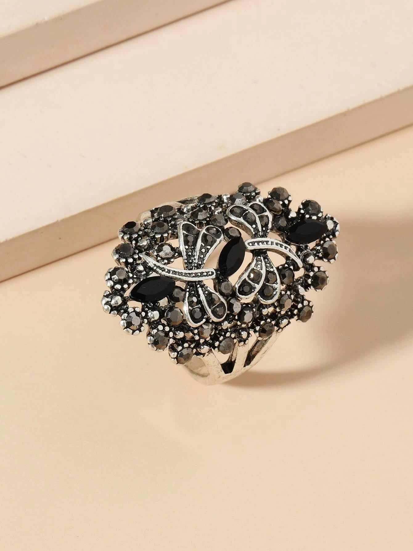 An exquisite dragonfly-themed ring adorned with rhinestones. The ring showcases a detailed dragonfly motif crafted with shimmering rhinestones, creating a captivating and whimsical look. The combination of the intricate design and the sparkling gems adds an element of elegance and charm to this accessory. A fashionable and unique piece of jewelry that can elevate various outfits.