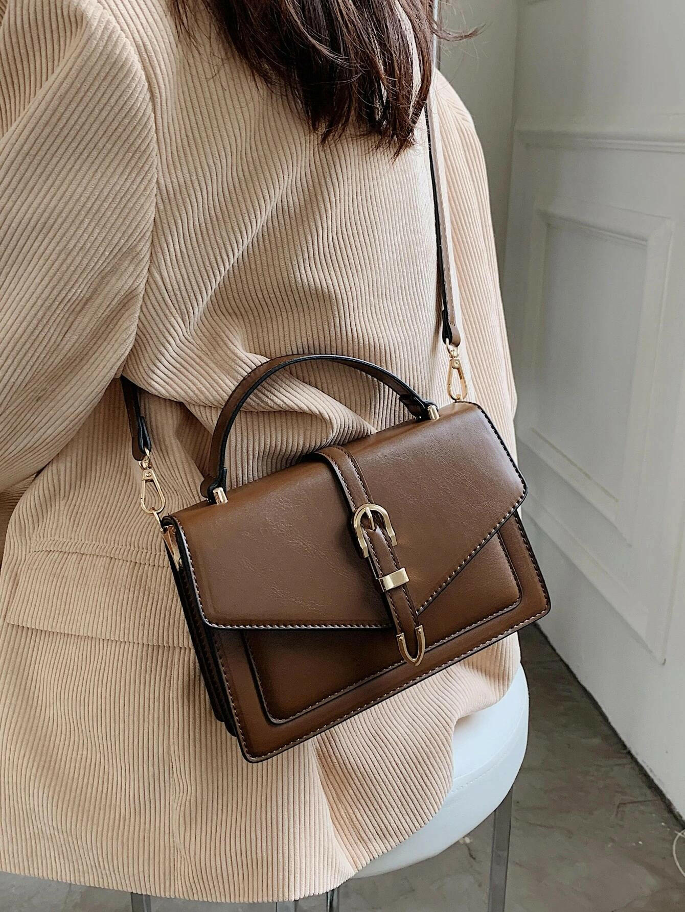 Square bag with flap closure and buckle decoration. This stylish accessory blends modern design with classic elements, offering both functionality and a fashionable touch.
