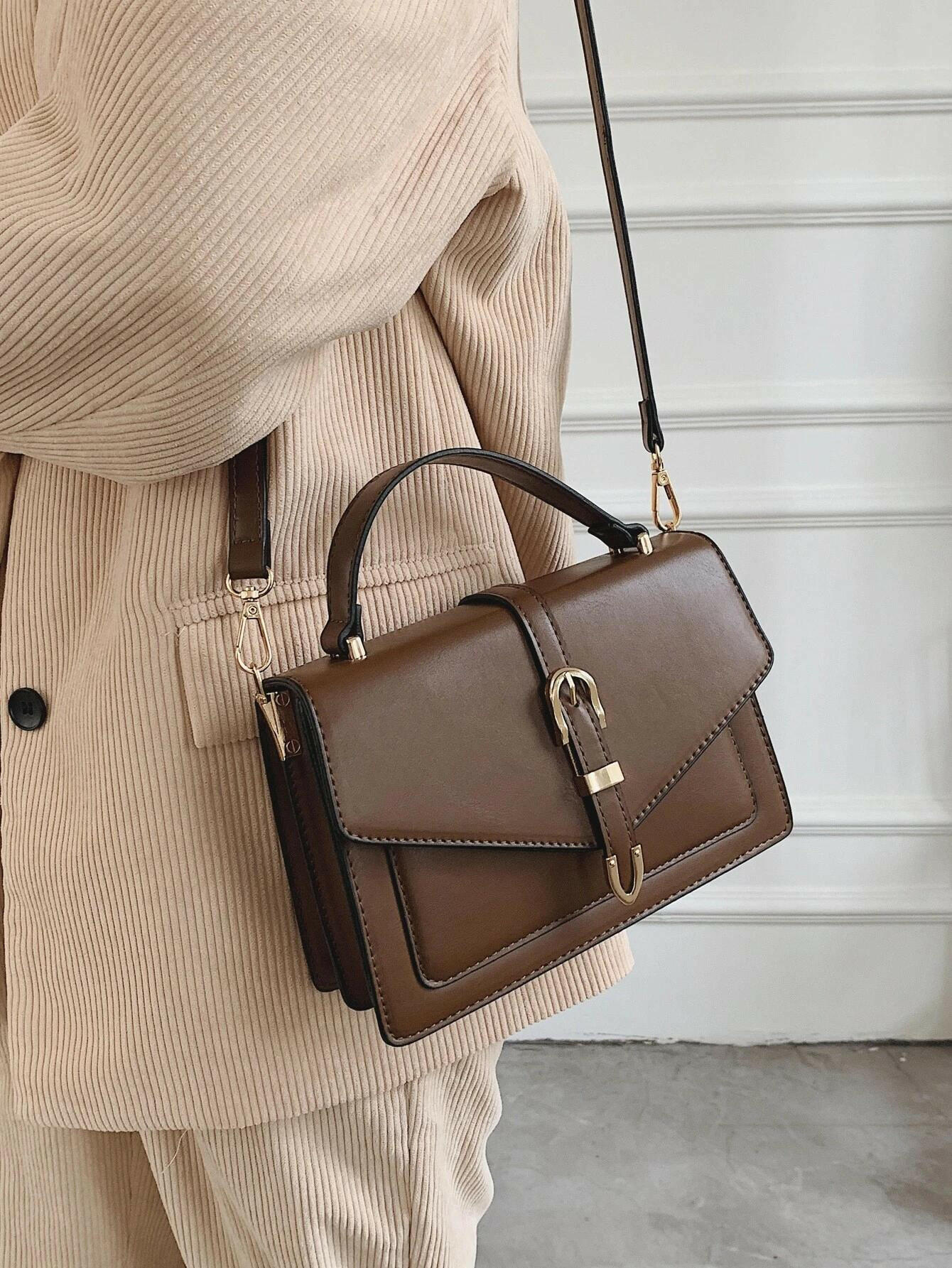 Square bag with flap closure and buckle decoration. This stylish accessory blends modern design with classic elements, offering both functionality and a fashionable touch.