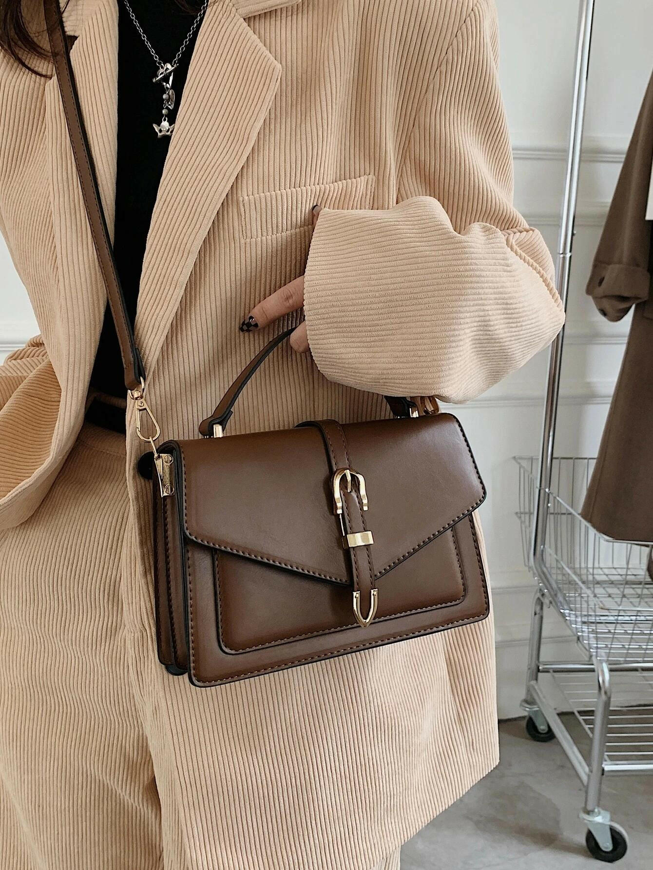 Square bag with flap closure and buckle decoration. This stylish accessory blends modern design with classic elements, offering both functionality and a fashionable touch.