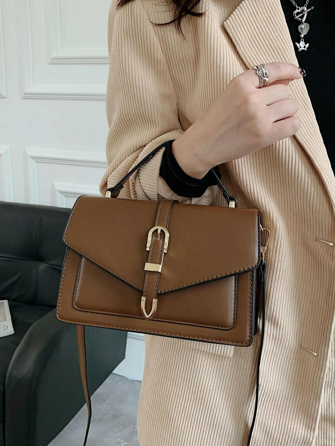 Square bag with flap closure and buckle decoration. This stylish accessory blends modern design with classic elements, offering both functionality and a fashionable touch.