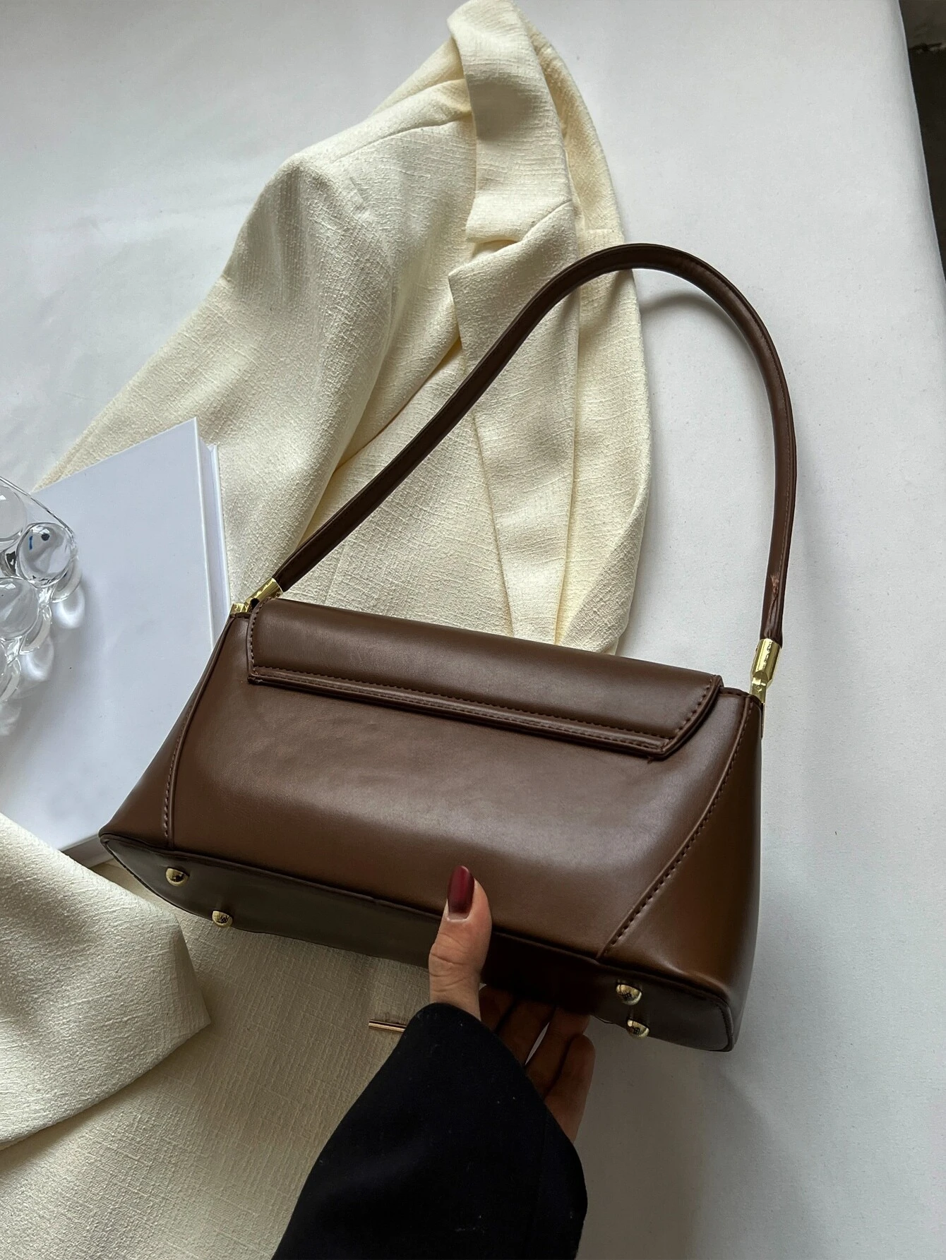 Flap baguette bag adorned with metal decorative elements. This accessory blends modern design with stylish embellishments, offering a chic and eye-catching way to carry your essentials.