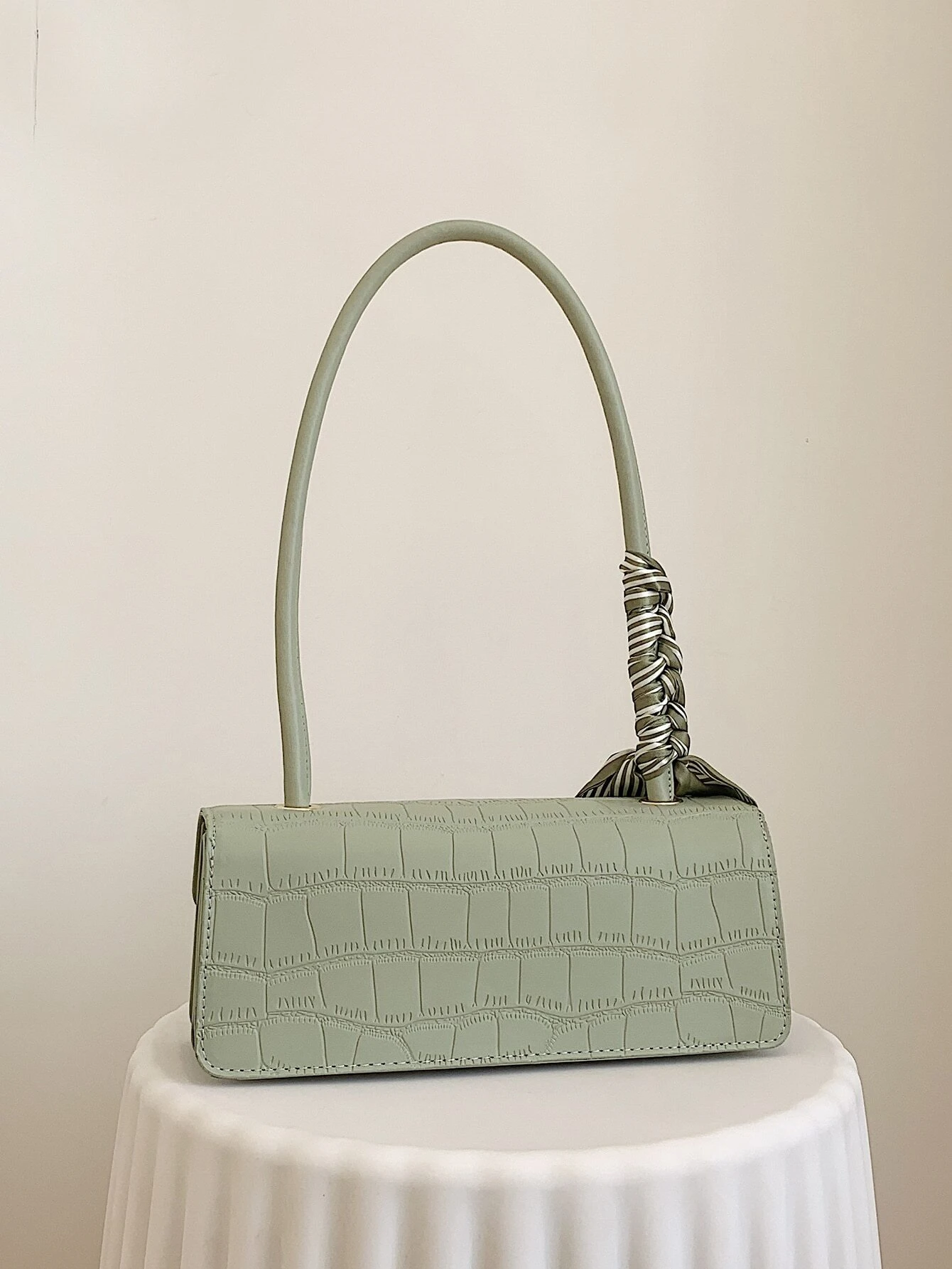 Crocodile embossed flap square bag with twilly decoration. This accessory blends sophisticated texture with stylish embellishments, offering a chic and visually appealing way to carry your essentials.