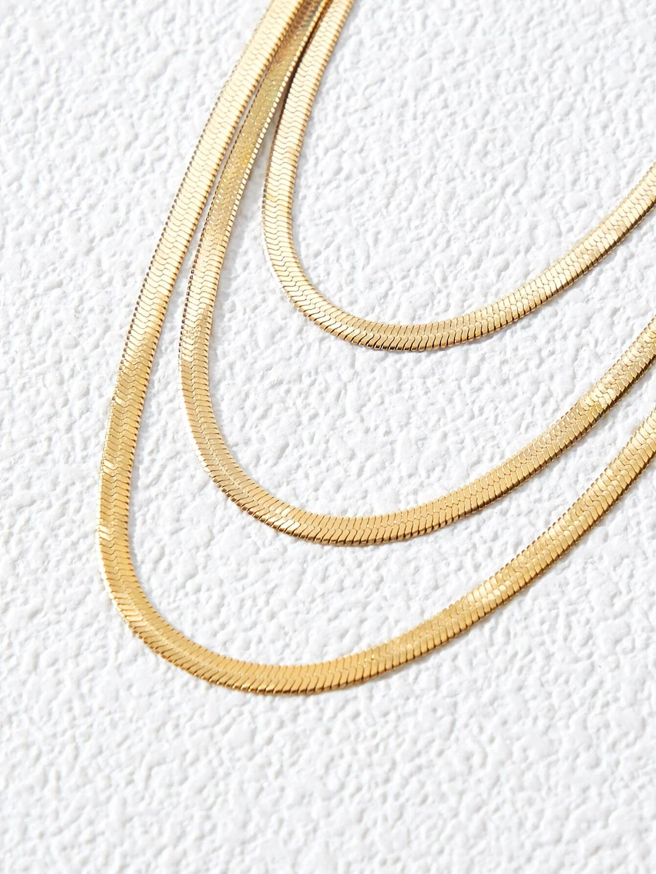 A layered necklace with a minimalist design. The necklace features delicate chains arranged in layers, creating a simple and elegant look. This accessory is modern and versatile, adding a touch of understated sophistication to various outfits