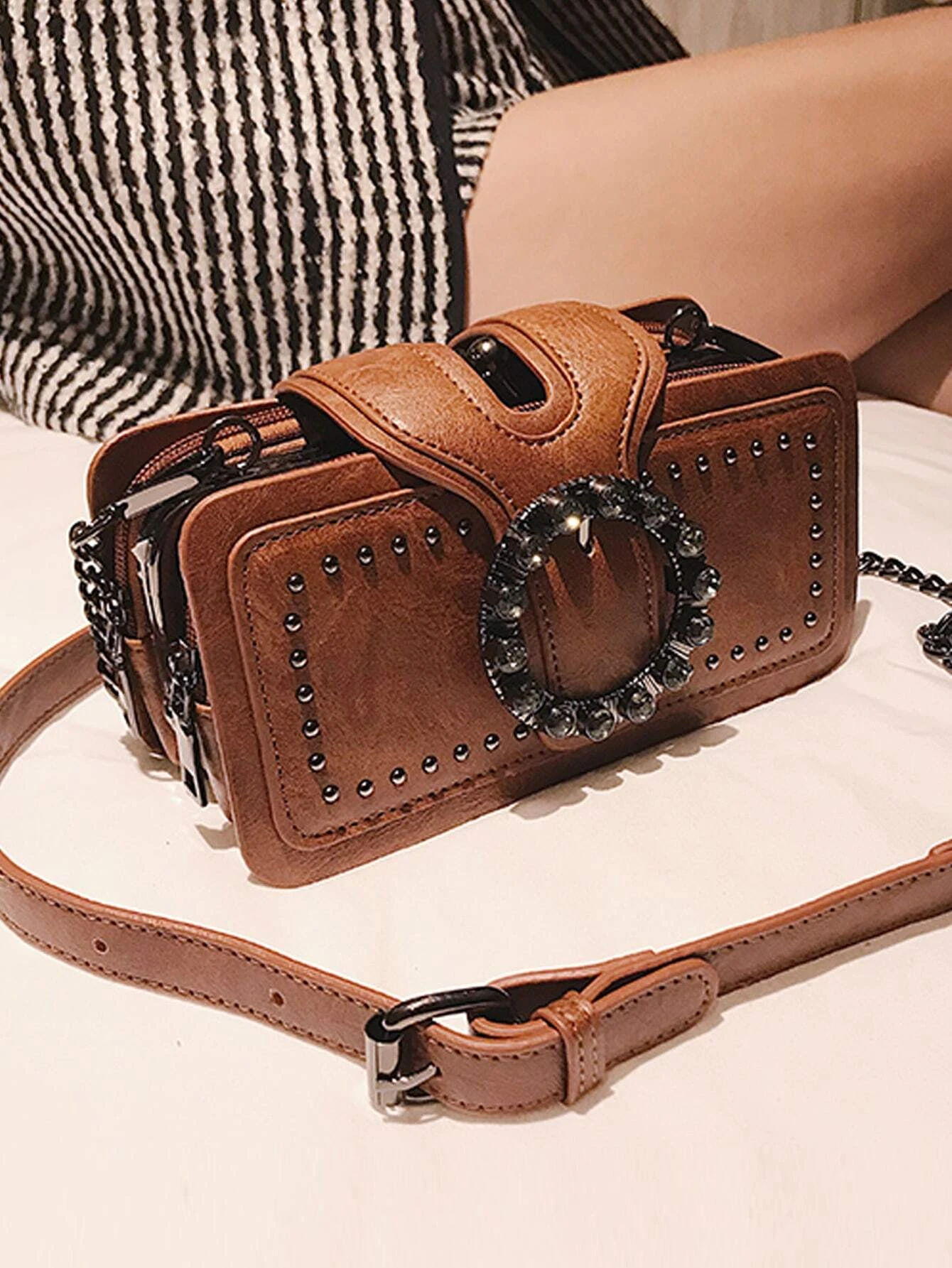 Square bag adorned with studded and buckle decorations. This accessory adds a touch of edgy style to your ensemble, featuring a combination of studs and buckles that enhance its visual appeal.