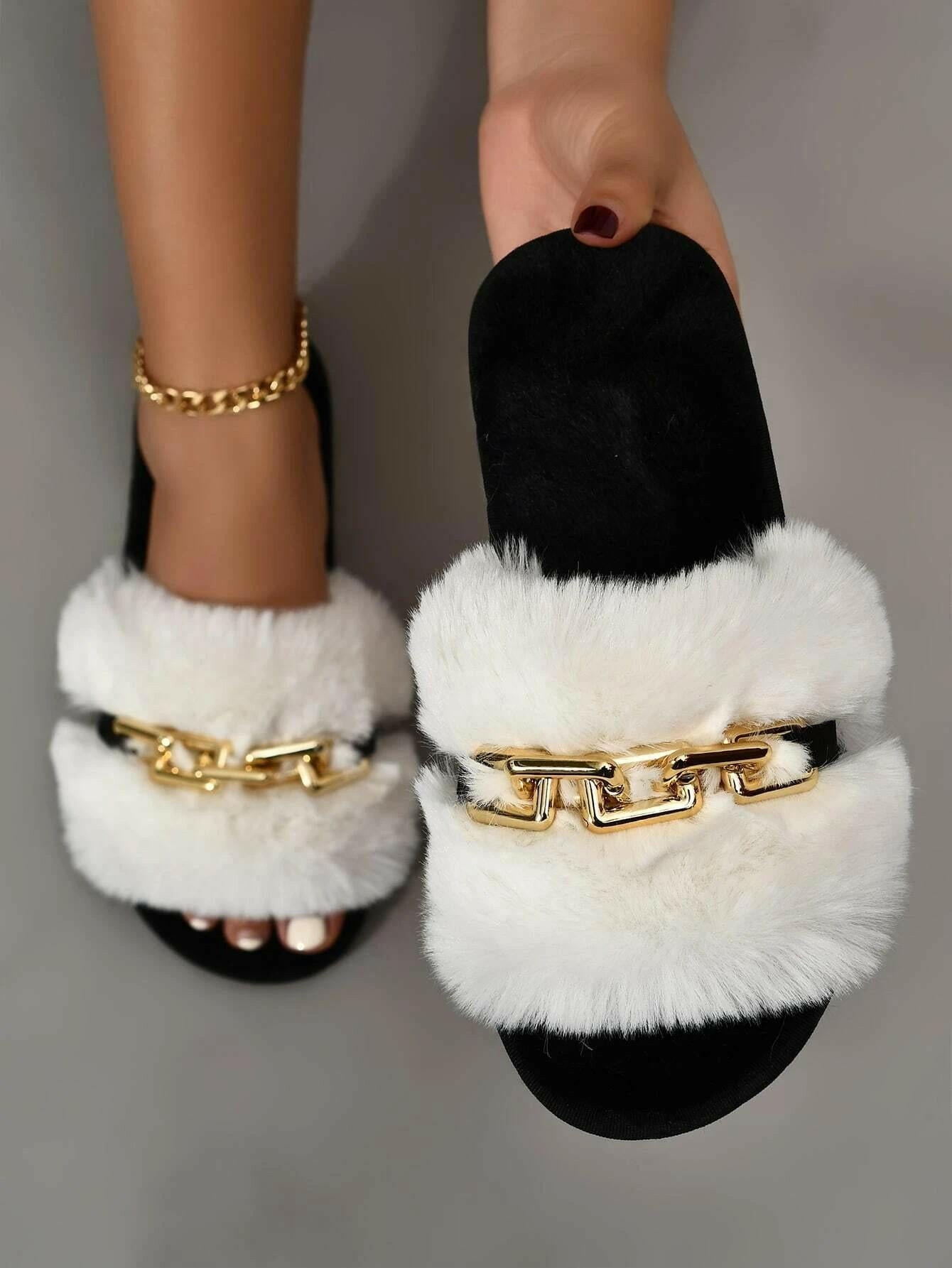 Fuzzy slippers enhanced with chain embellishments, blending comfort with a hint of elegance. The slippers showcase a fuzzy texture that envelops the feet in warmth, while dainty chains provide a stylish decorative element, perfect for indoor relaxation.