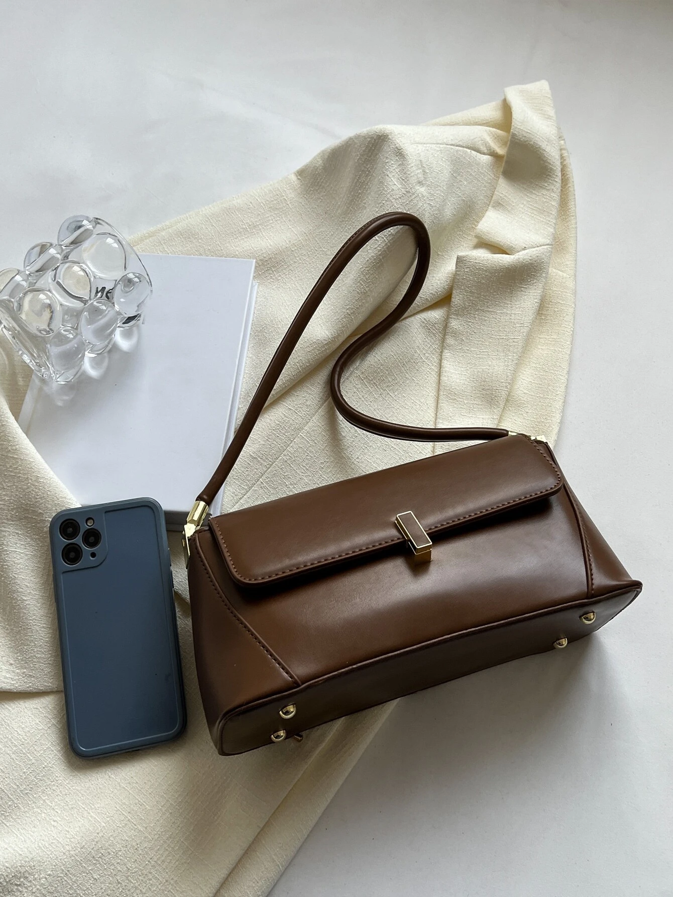 Flap baguette bag adorned with metal decorative elements. This accessory blends modern design with stylish embellishments, offering a chic and eye-catching way to carry your essentials.