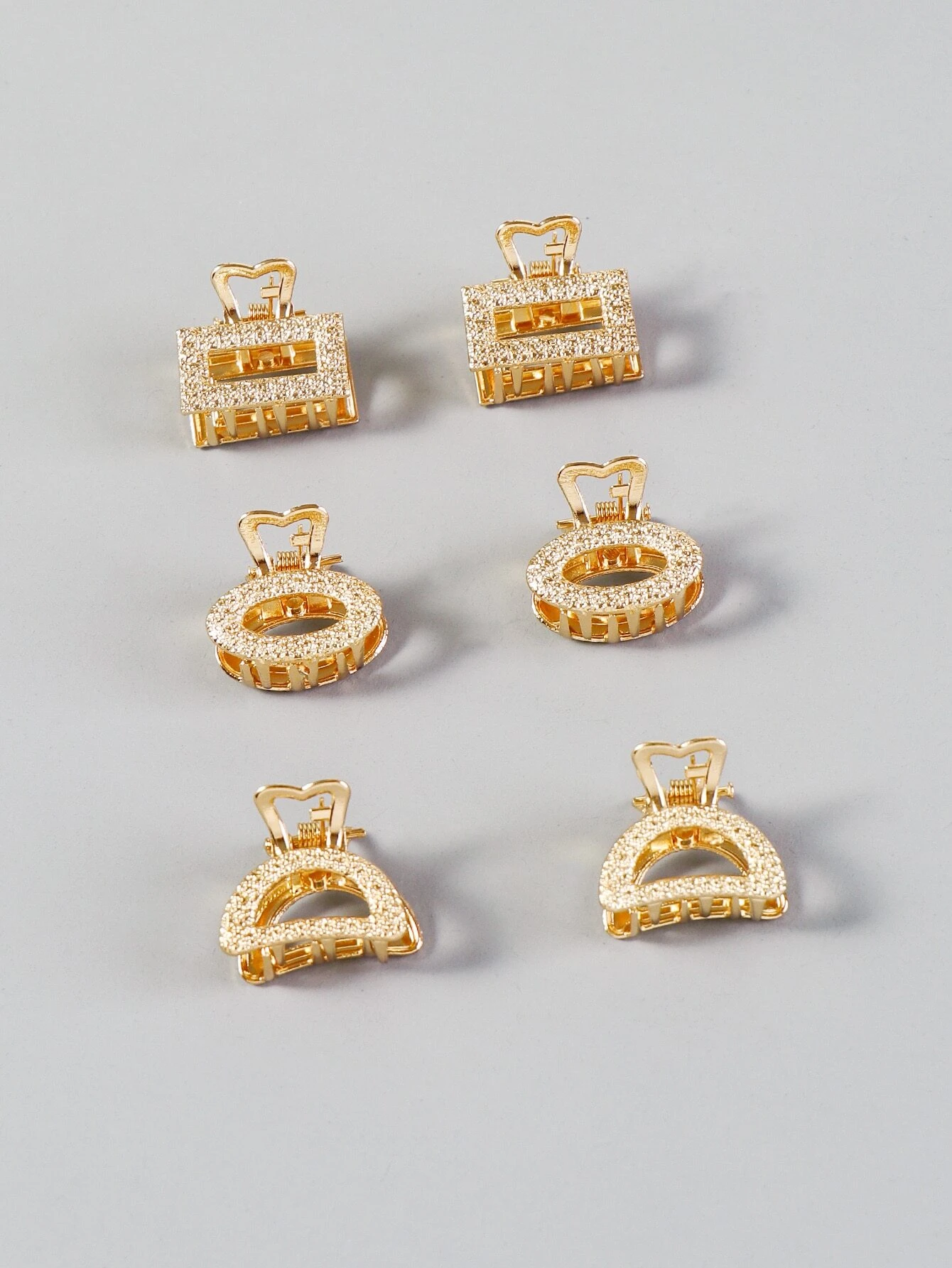 A set of six metallic hair claws, providing a sleek and modern way to secure and style your hair with a touch of shine.