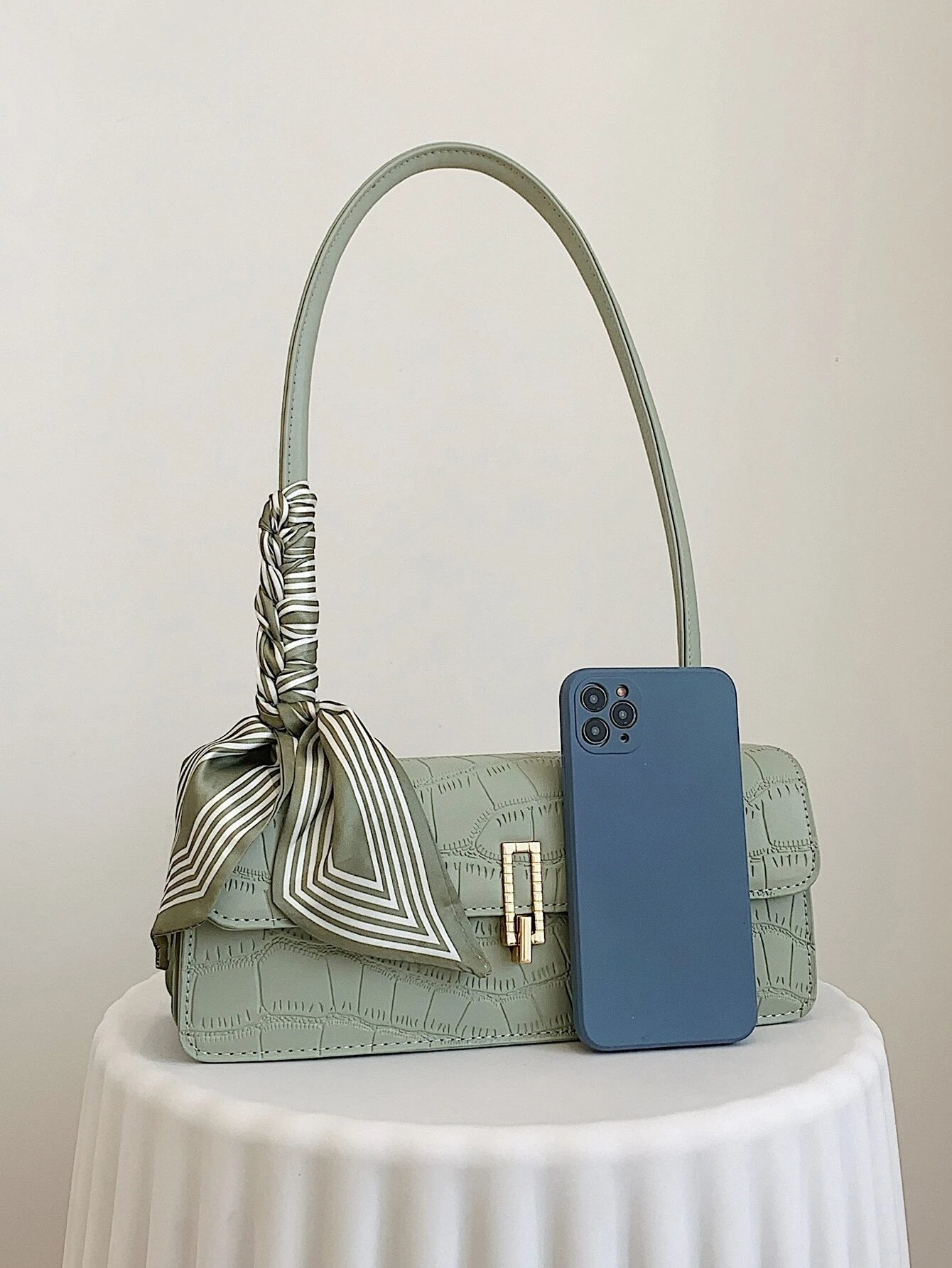 Crocodile embossed flap square bag with twilly decoration. This accessory blends sophisticated texture with stylish embellishments, offering a chic and visually appealing way to carry your essentials.