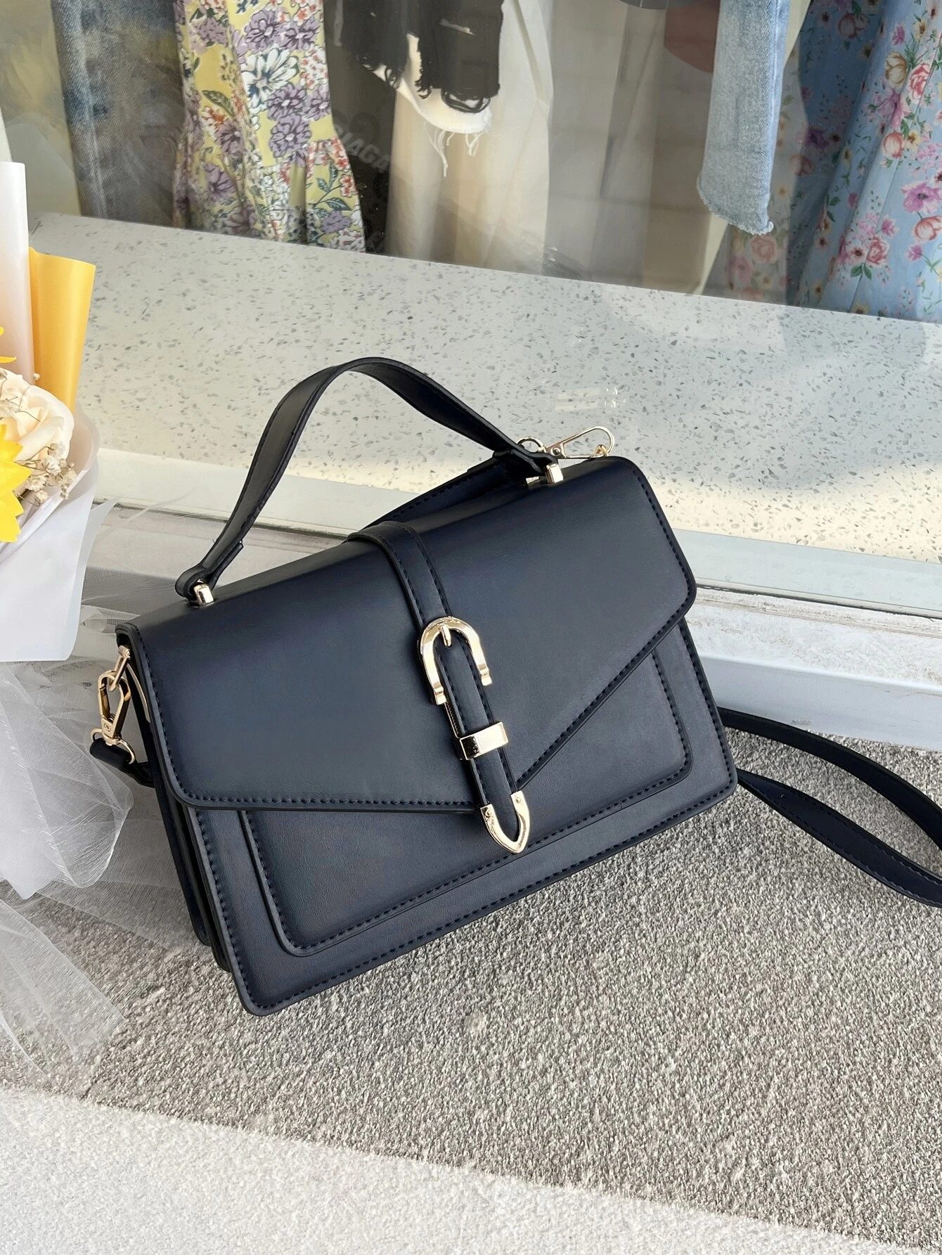 Minimalist navy blue square bag with metal decorative elements and flap closure. This accessory combines modern design with stylish embellishments, offering a chic and visually appealing way to carry your essentials.